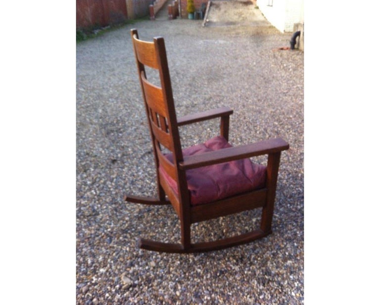 Stickley Brothers in the style of.
A good quality American Arts and Crafts oak rocking chair, with a stylish curved and slatted back and a burgundy leather cushion.