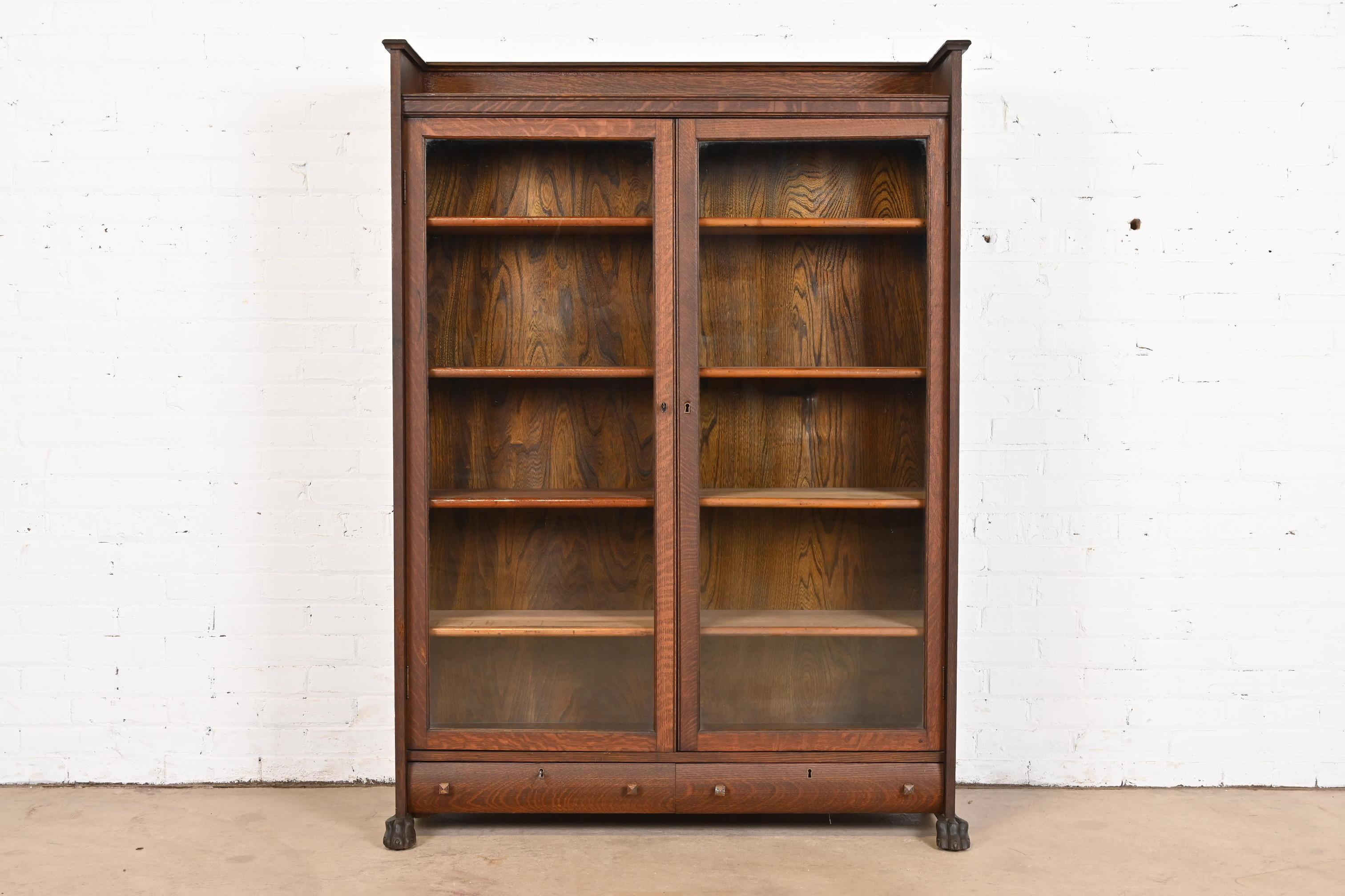A gorgeous antique Mission or Arts & Crafts double bookcase cabinet over two drawers

In the manner of Stickley Brothers

USA, Circa 1900

Oak, with carved paw feet, glass front doors, and copper drawer pulls. Cabinet locks, and key is