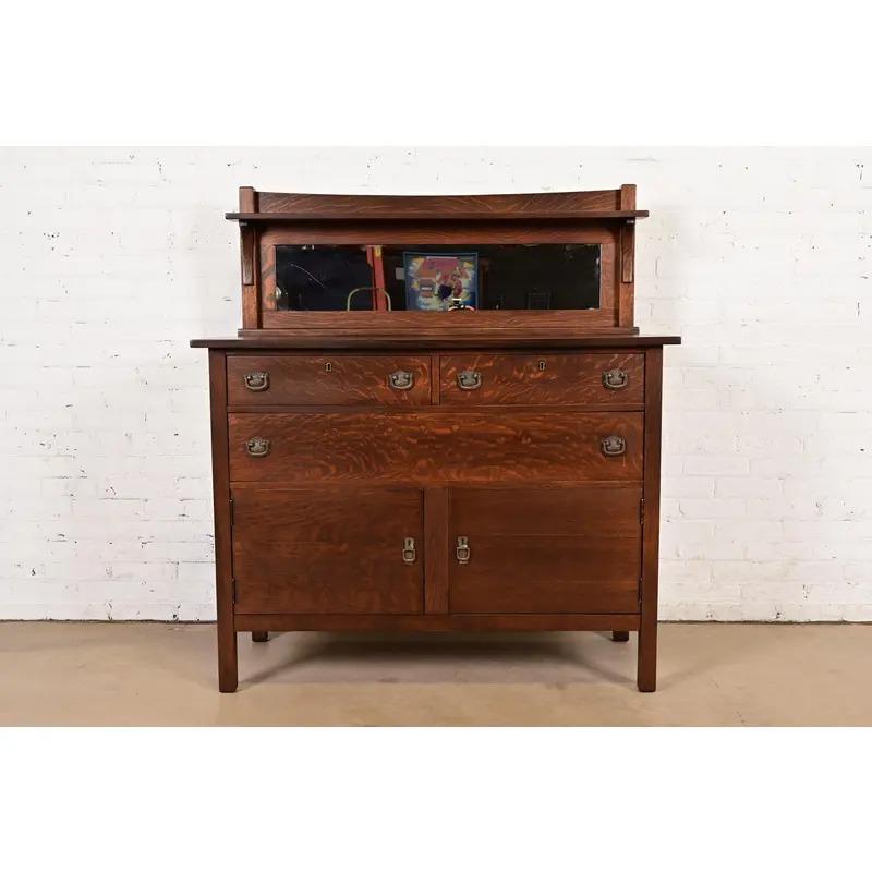 A gorgeous antique Mission or Arts & Crafts sideboard, buffet server, or bar cabinet

In the manner of Stickley Brothers

USA, Circa 1900

Quarter sawn oak, with mirrored backsplash, and original hammered copper hardware.

Measures: 48