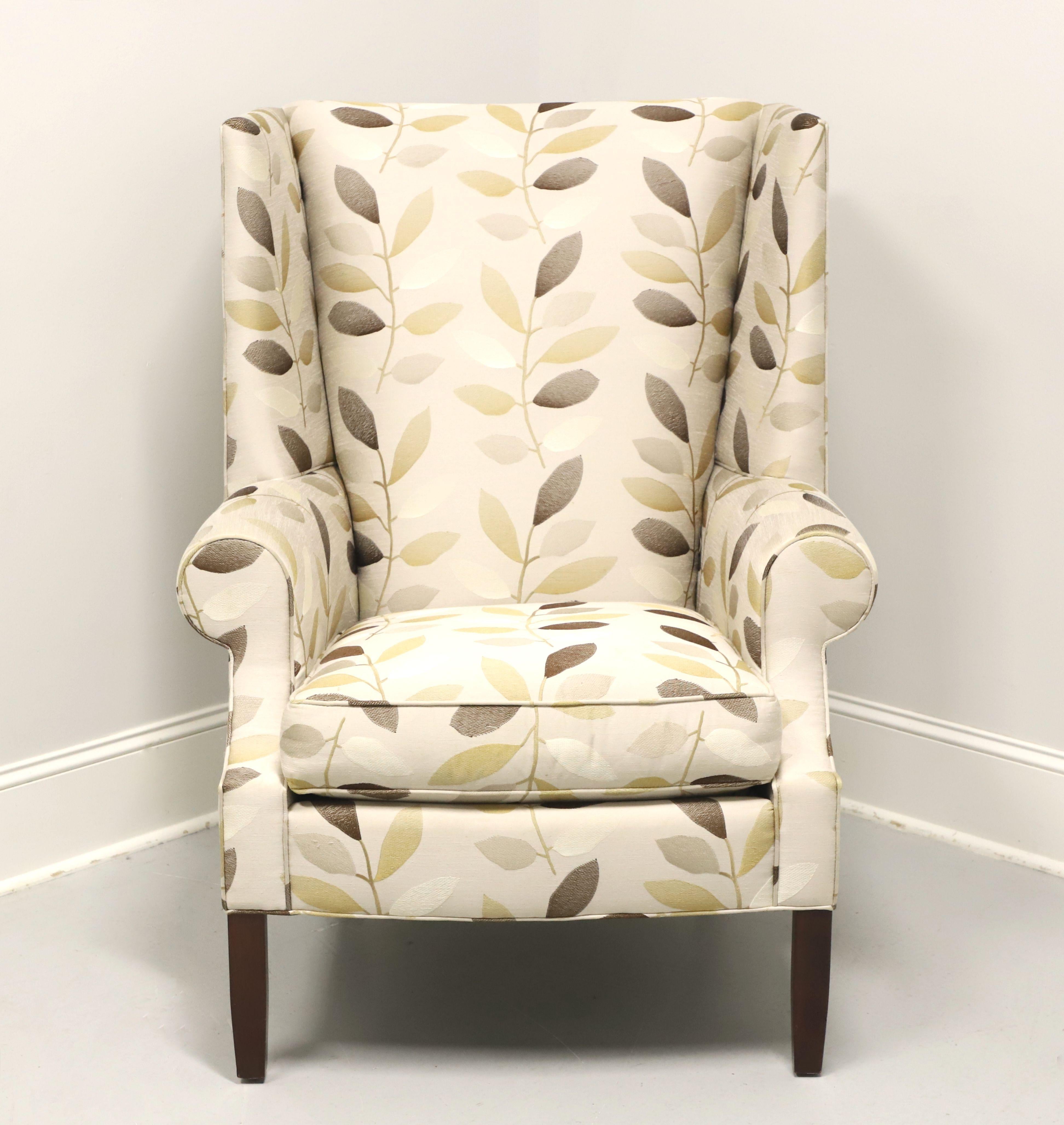 A Transitional style wing back chair by Stickley Furniture, their Park City. Fabric upholstered in a pattern of various neutral tone leaves amidst a beige color base on a cherry wood frame with their Metro finish to the tapered straight front legs
