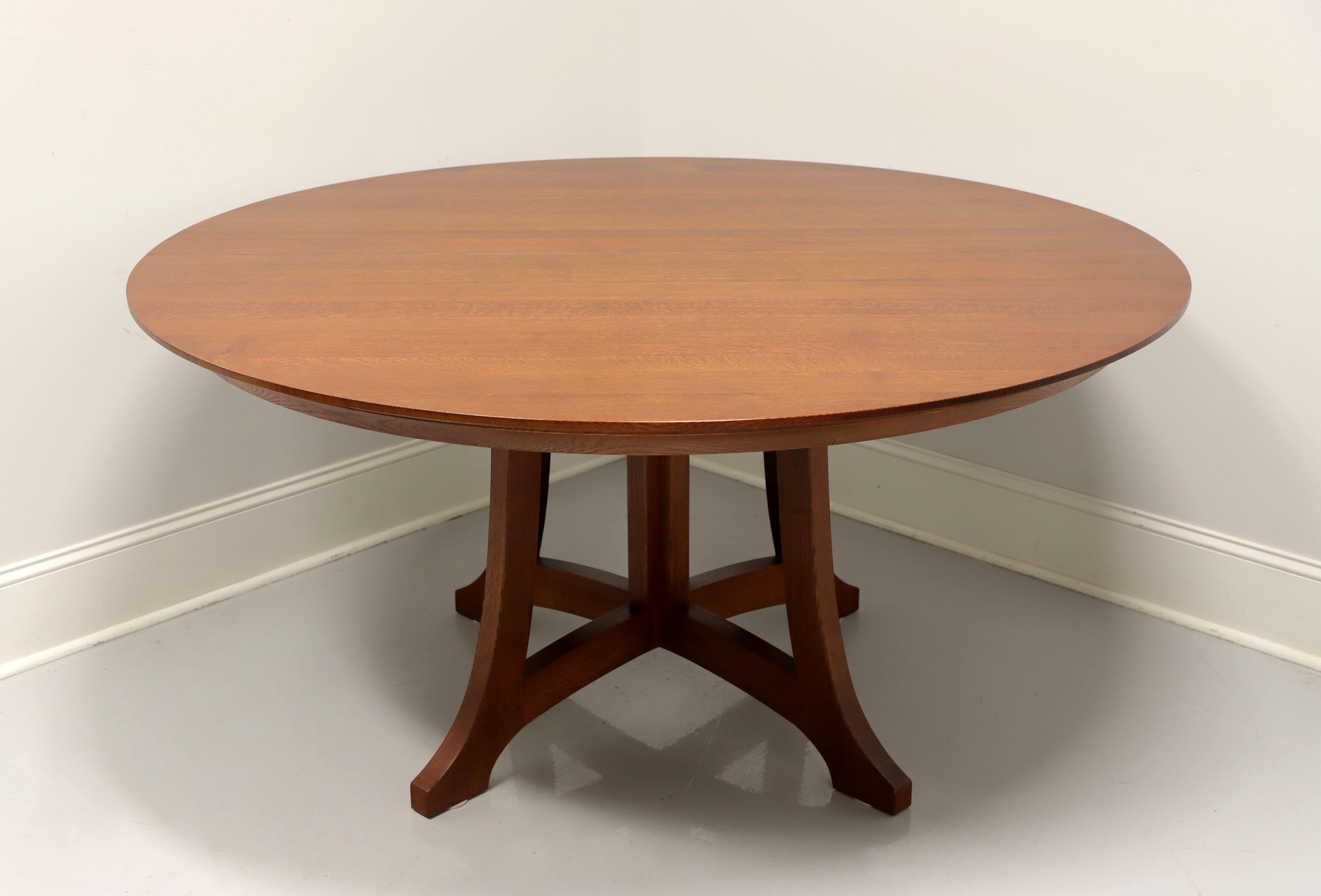 A Mission / Arts & Crafts style 62 inch round dining table by Stickley, from their Highlands Collection. Solid oak with a darker finish, a distinctive split pedestal base and metal expansion sliders. Includes two expansion leaves. Made in Manlius,