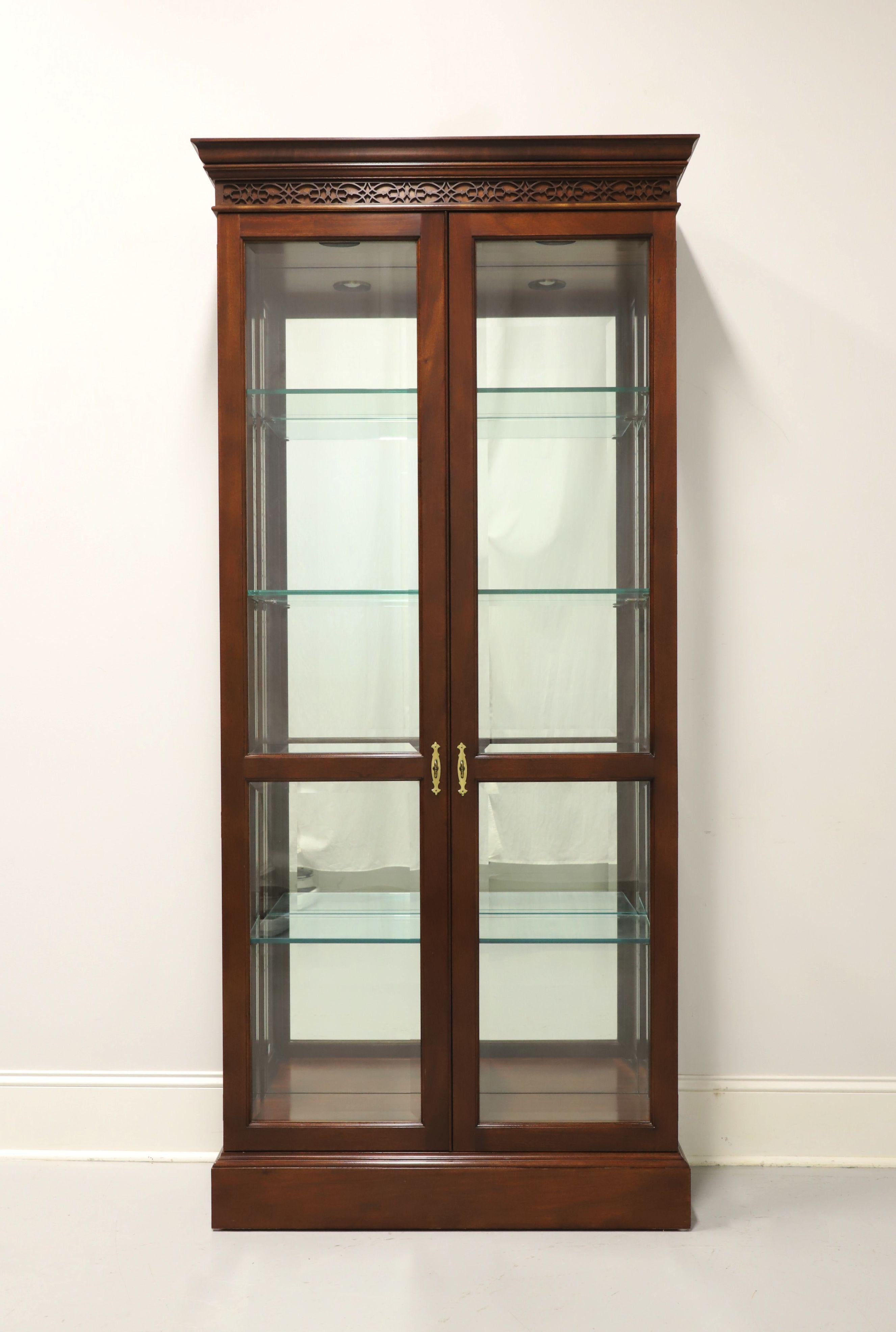 A Chippendale style curio display cabinet by Stickley Furniture. Solid mahogany with brass hardware, decorative fretwork to frieze at top, beveled glass dual doors and beveled side panels. Lighted cabinet features a mirrored back, a fixed center