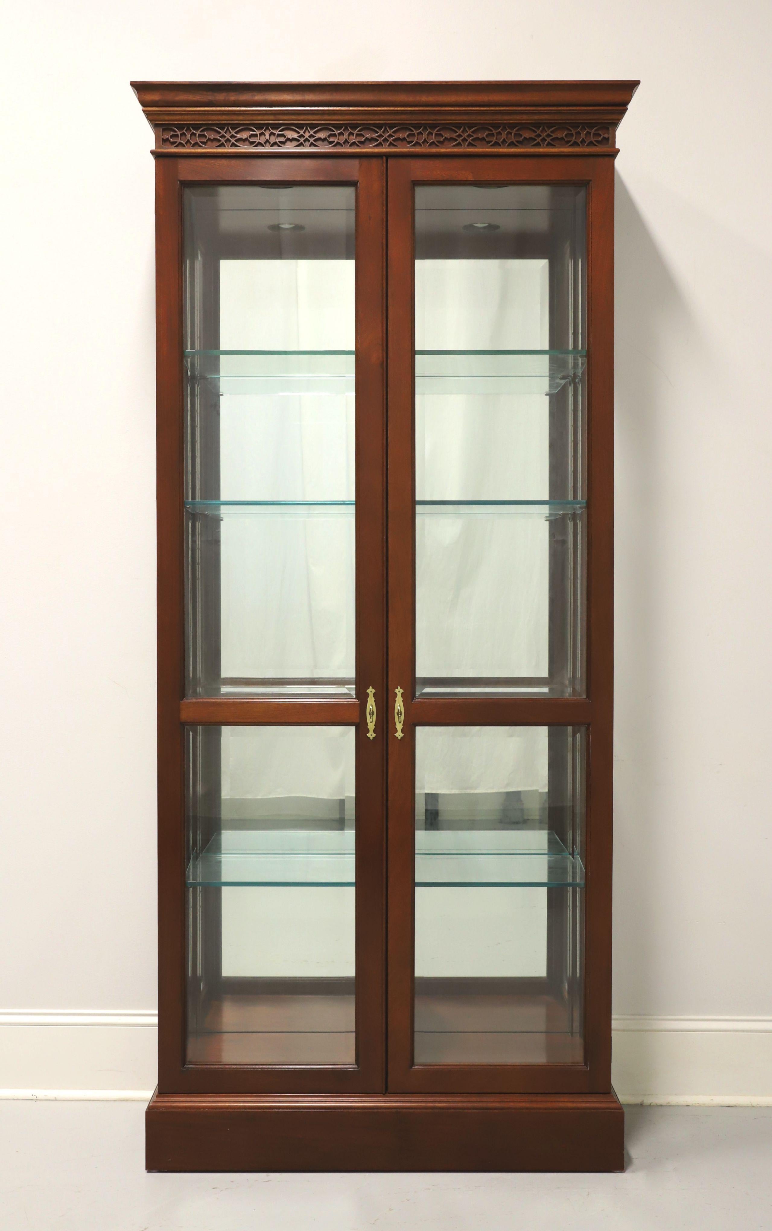 A Chippendale style curio display cabinet by Stickley Furniture. Solid mahogany with brass hardware, decorative fretwork to frieze at top, beveled glass Dual doors and beveled side panels. Lighted cabinet features a mirrored back, a fixed center