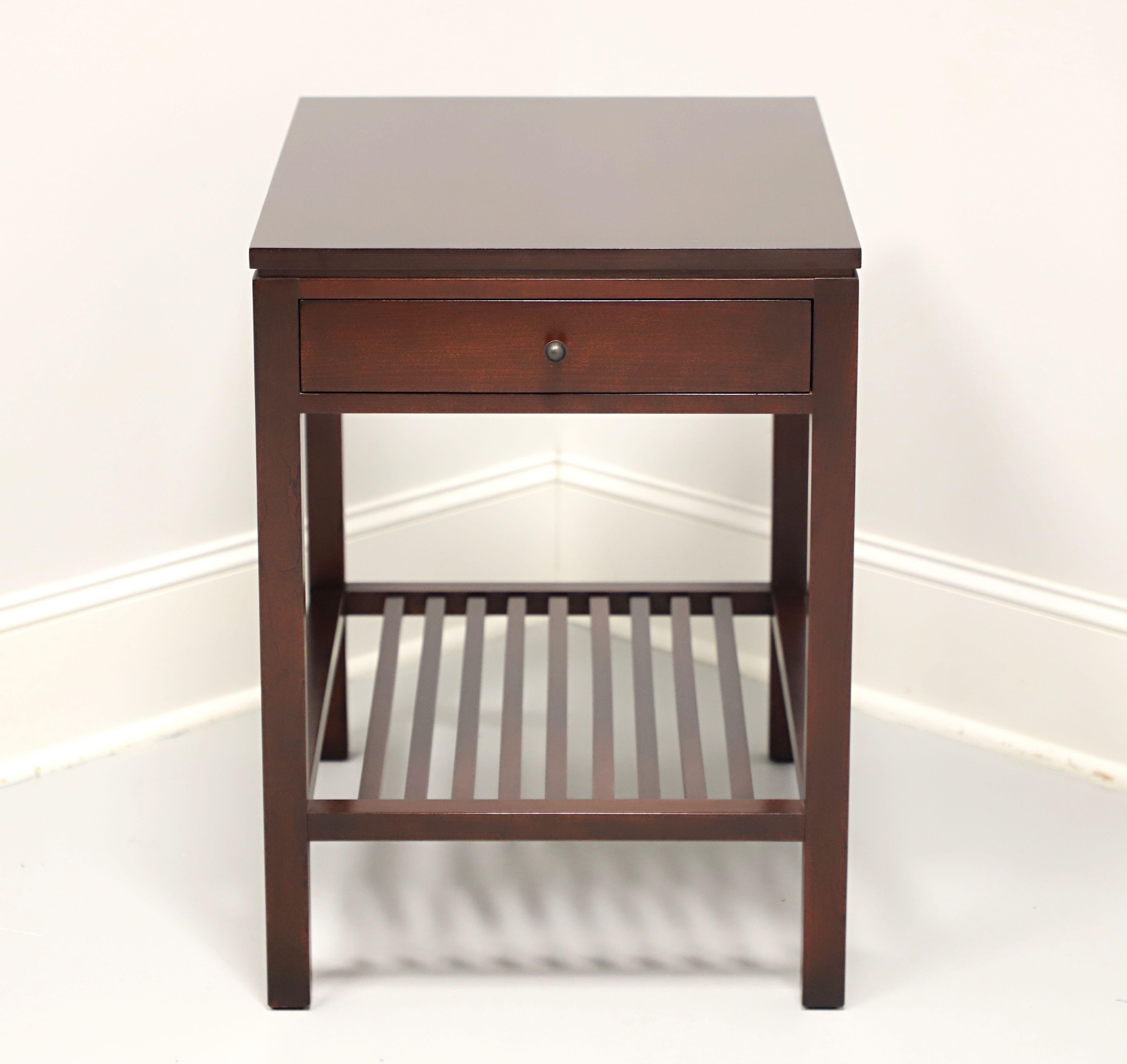 A Modern Contemporary style end table by Stickley Furniture, from their Metropolitan Collection. Cherry wood with their Saratoga finish, square edge to top, dark copper hardware, open slat undertier shelf, and square straight legs. Features one