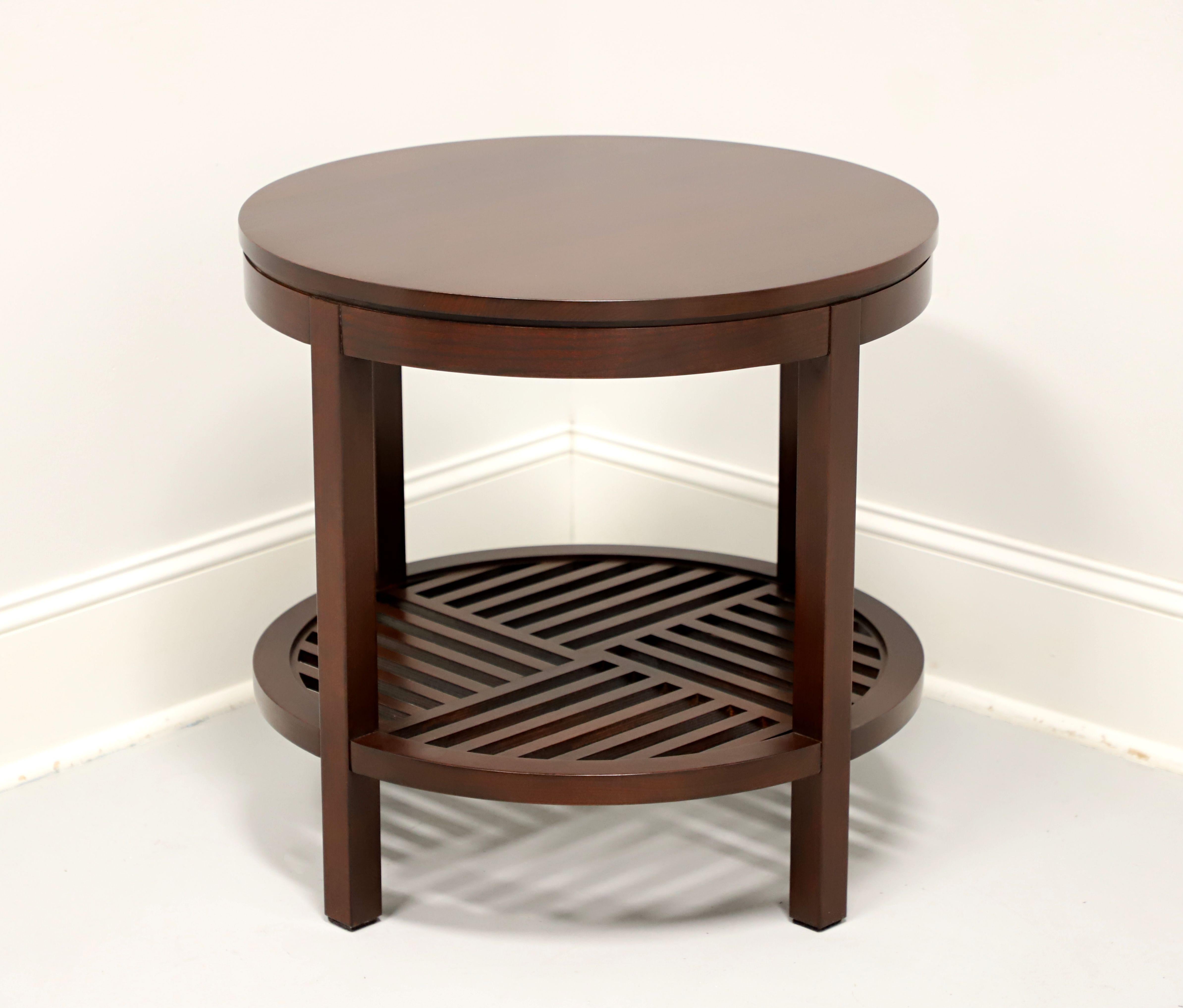 A Modern Contemporary style round lamp table by Stickley Furniture, from their Metropolitan Collection. Cherry wood with their Saratoga finish, smooth edge to top & apron, open slat undertier shelf in a geometric design, and square straight legs.