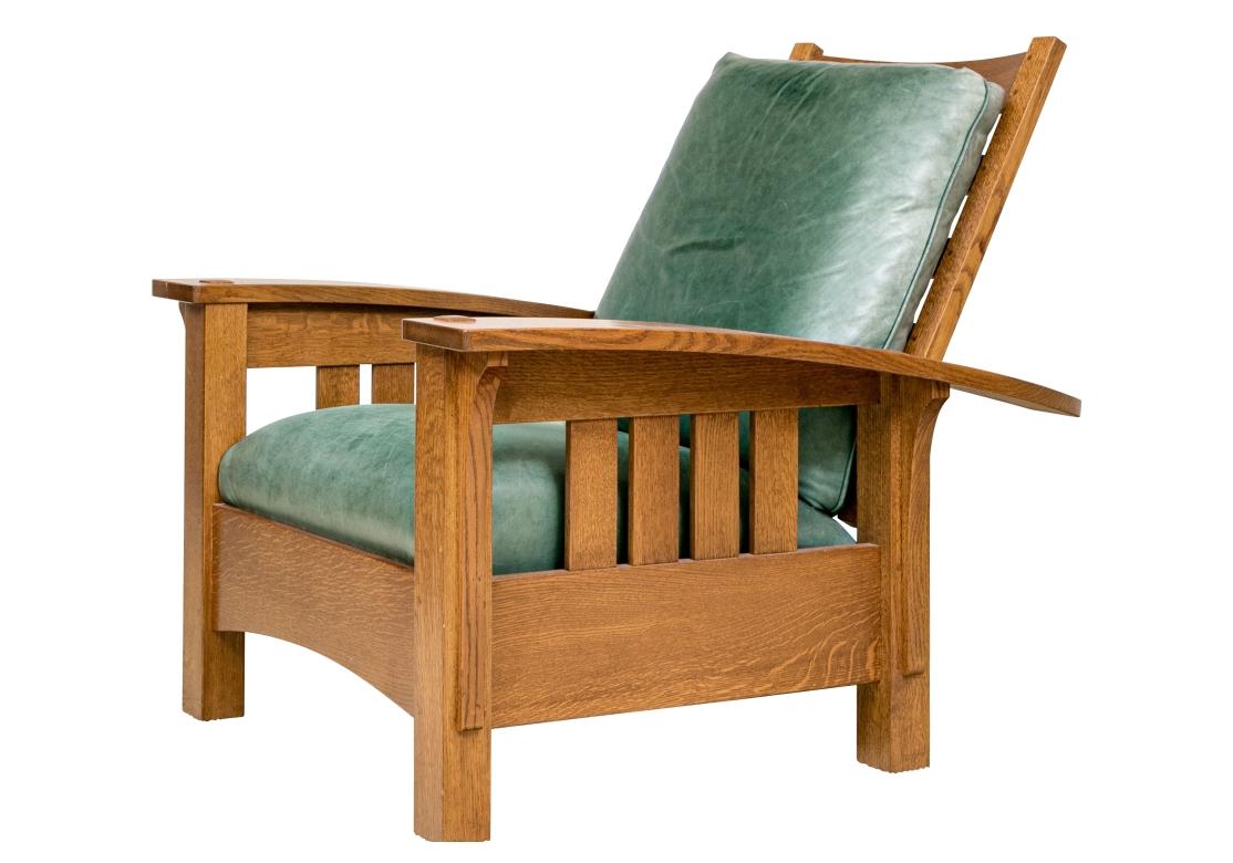 Stickley Mission Collection oak bow arm reclining chair with slatted construction, adjustable back, elongated corbel motifs beneath the arms, pyramidal motifs, green leather cushions and resting on square feet. The reclining chair bears the shopmark
