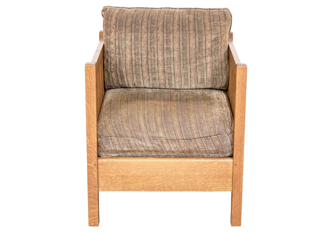 A handsome Mission style armchair in honeyed medium-light brown tiger oak, displaying a spindle back frame with equal height arms and a wide, straight apron. Topped with a loose back and seat cushion in striped neutrals.

Dimensions: 26.5” wide by