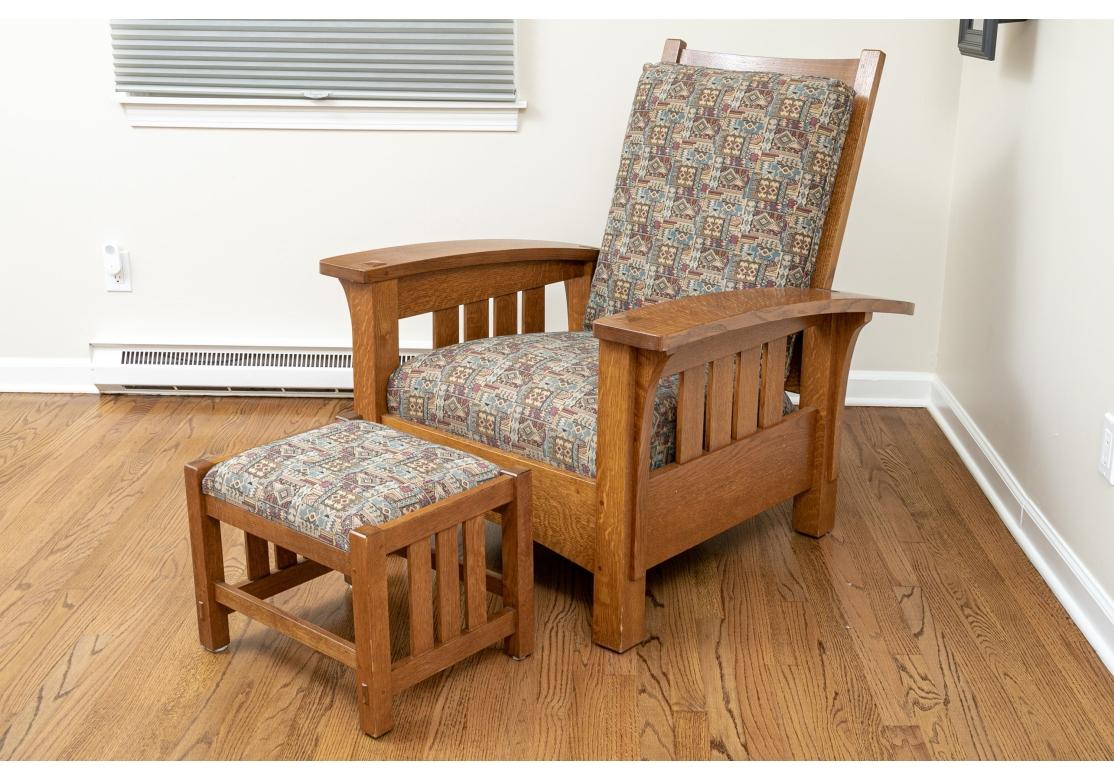 A fine Stickley solid oak lounge chair with loose pillow back, fixed seat and bowed arms. The fine craftsmanship of Stickley evident in the slatted construction and joinery. The pieces are covered in a multi-colored tapestry fabric. Manufactured