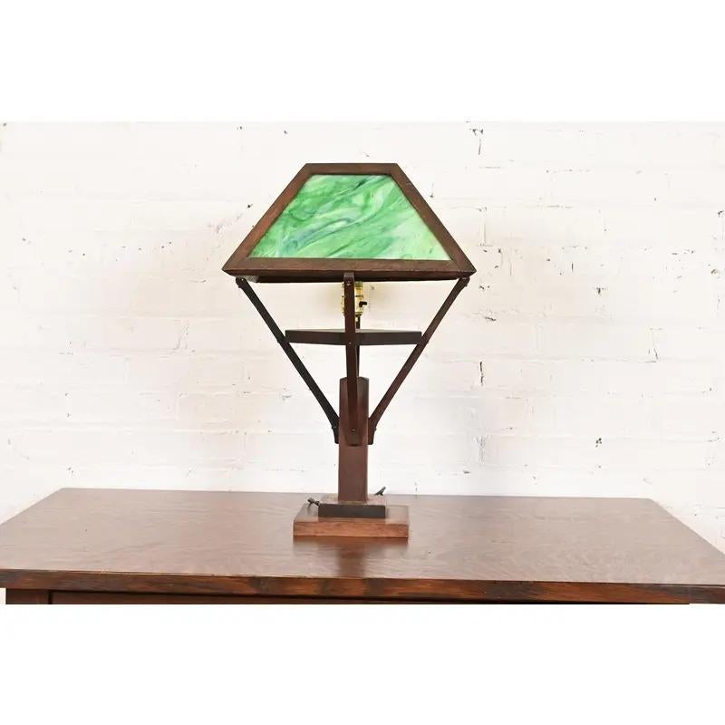 A gorgeous antique Mission or Arts & Crafts period table lamp 

In the manner of Stickley or Frank Lloyd Wright

USA, Circa 1920s

Carved oak, with beautiful green slag glass shade.

Measures: 14.25