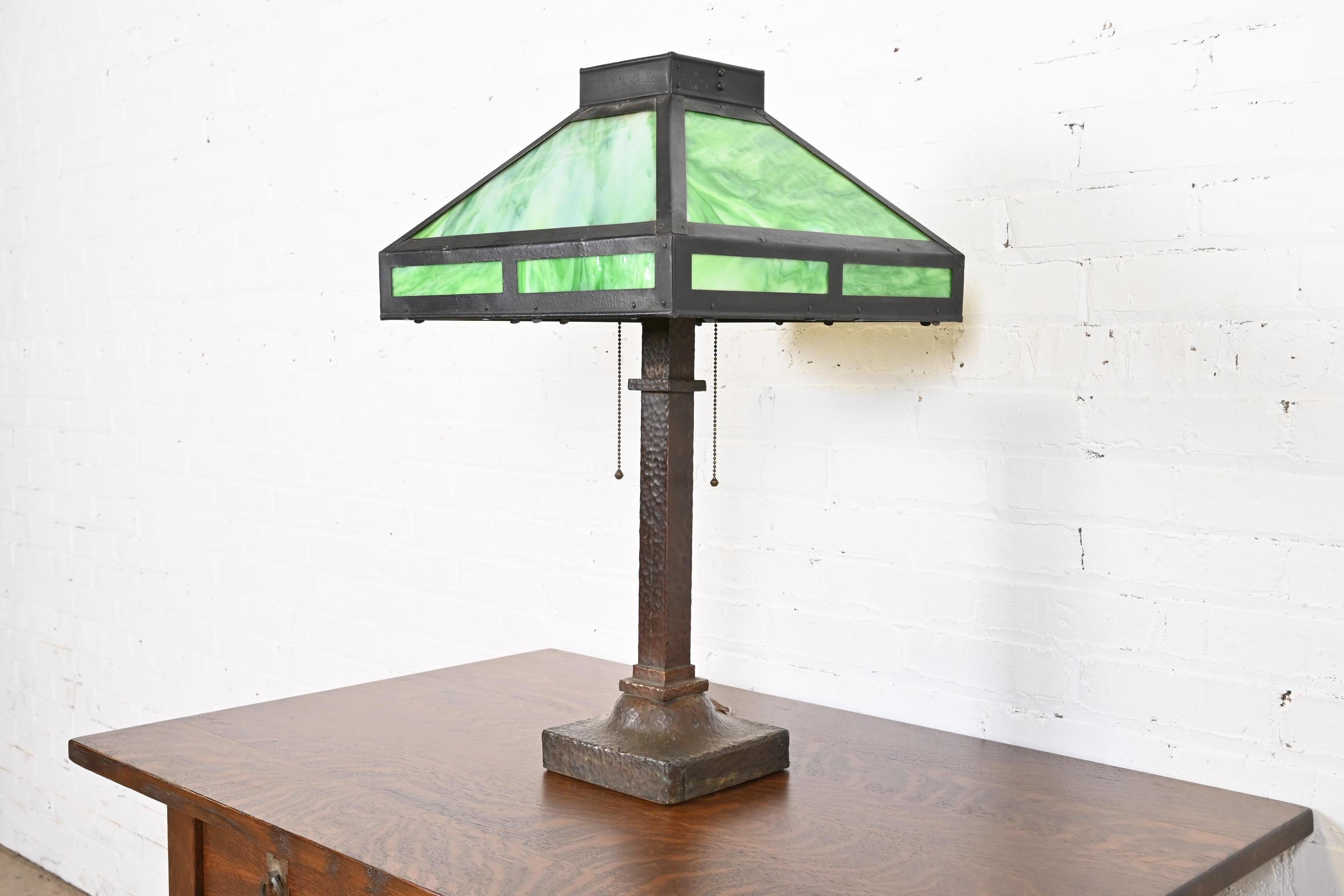 A gorgeous antique Mission or Arts & Crafts period table lamp 

In the manner of Stickley

USA, Circa 1920

Hammered copper base, with beautiful green slag glass shade.

Measures: 16.25