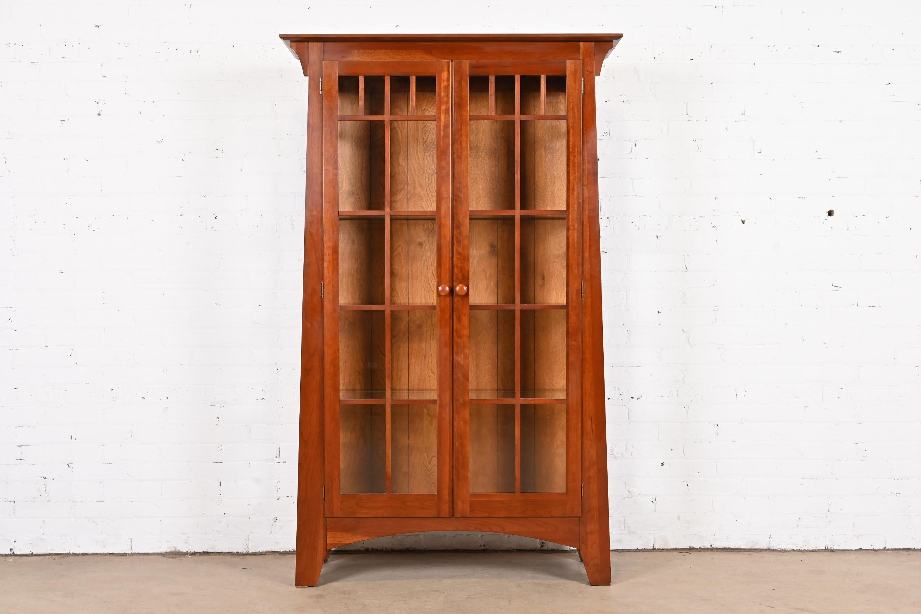 A gorgeous Mission or Arts & Crafts style lighted display cabinet or bookcase

In the manner of Gustav Stickley or Harvey Ellis

USA, circa late 20th century

Solid cherry wood, with mullioned glass front and sides.

Measures: 43