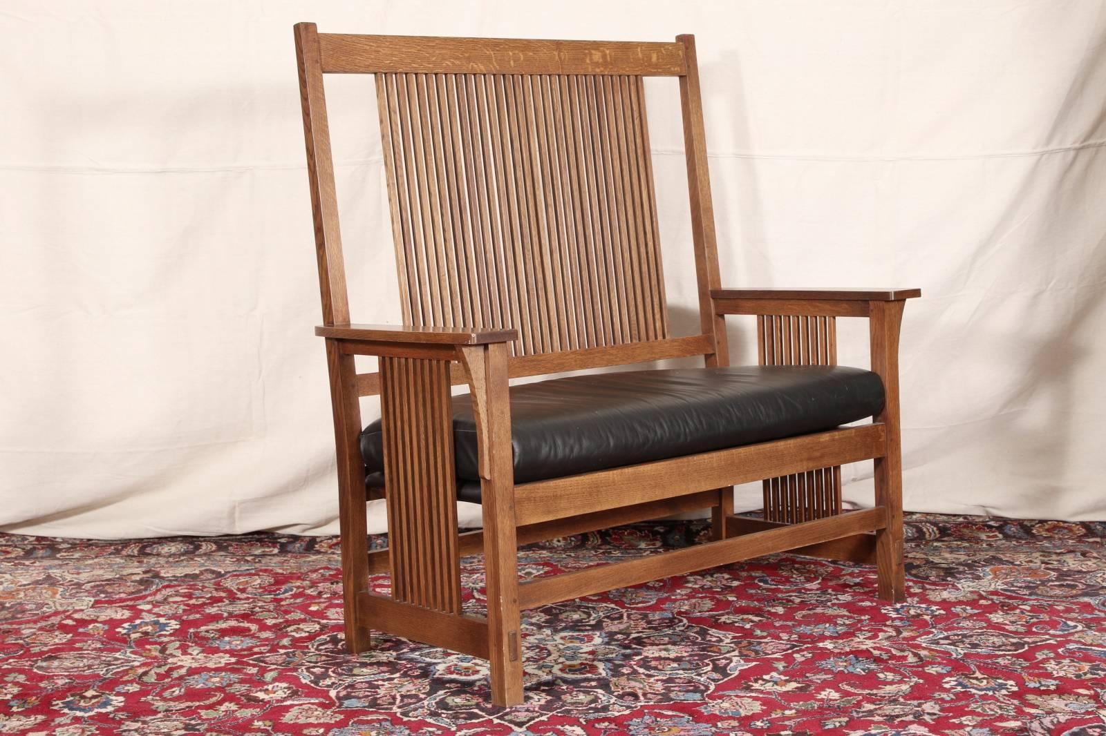 Stickley tall back settee with leather seat, slated back and sides, oak construction.

Condition: Expected wear and signs of use including stains to seat, but still presents very well.