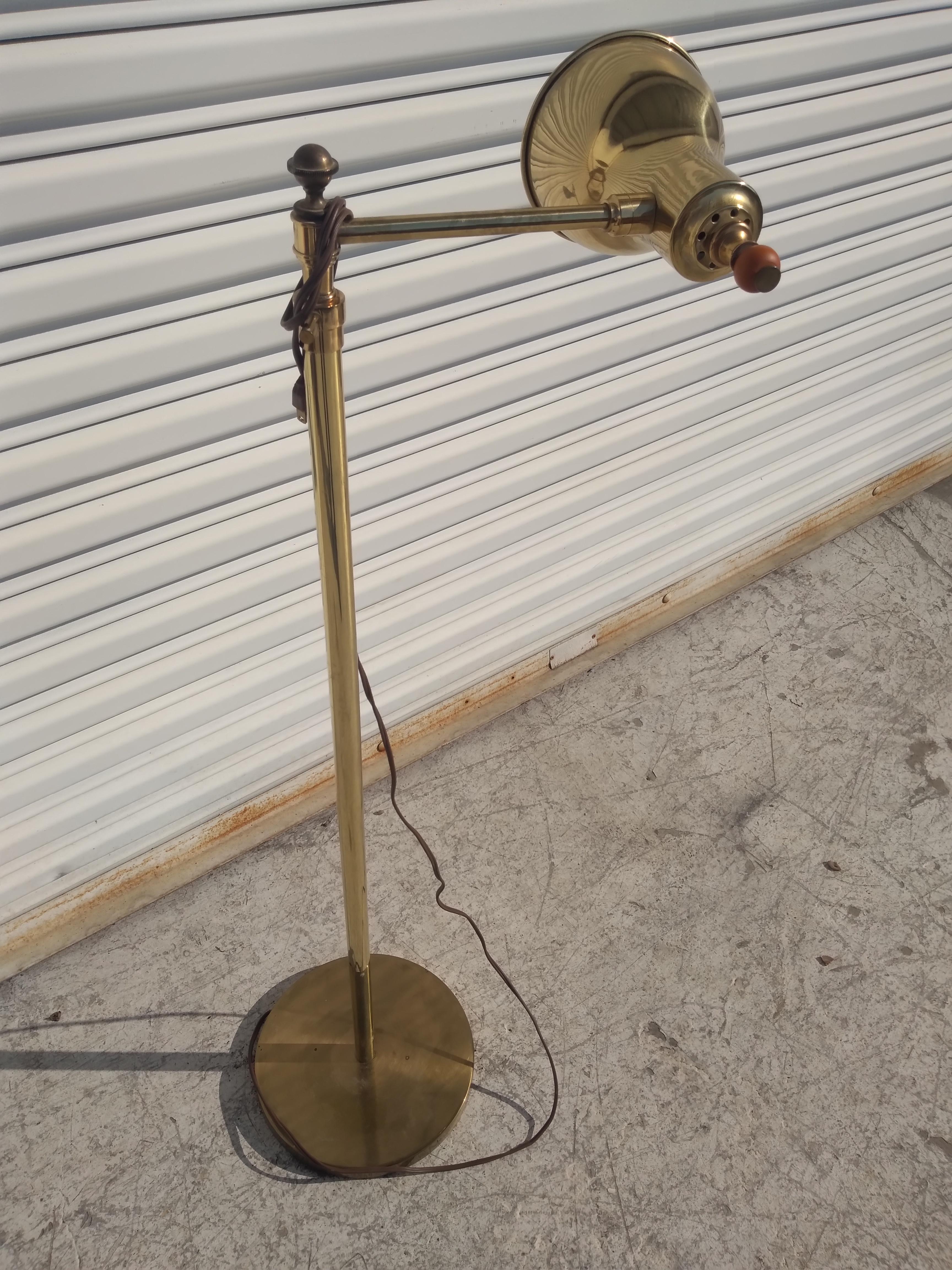 This is a swivel arm floor lamp. This floor lamp is made by the Stiffel Lighting Co. It's brass with a wooden knob on the shade. 

This lamp will make a great addition to any home.