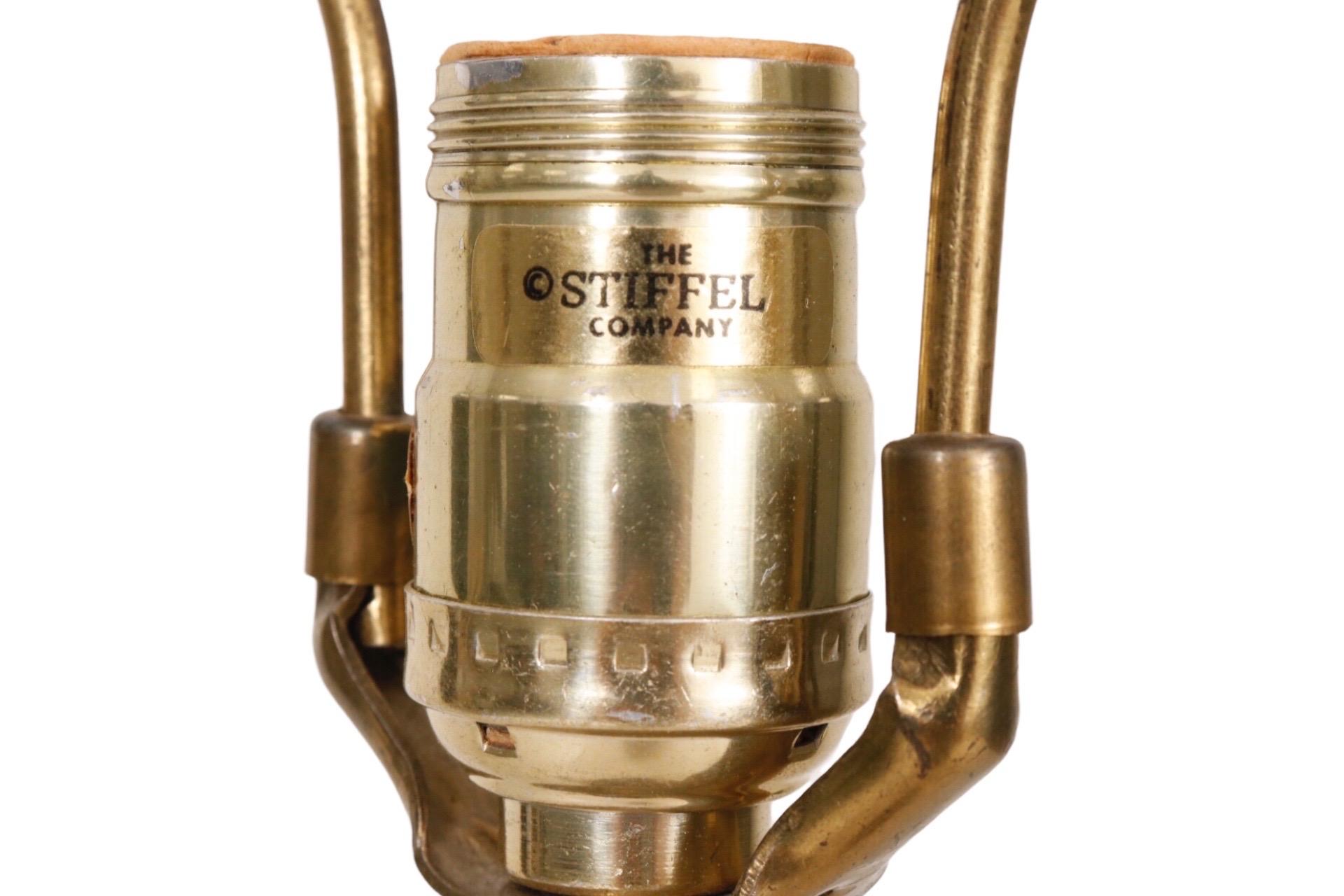 A Stiffel model #5561 table lamp in brass. Cast in a trophy style with curled acanthus leaves above a fluted urn. The small on-off rotary knob is on the base which is cast to give the look of being heavily turned. The Stiffel label can be seen on