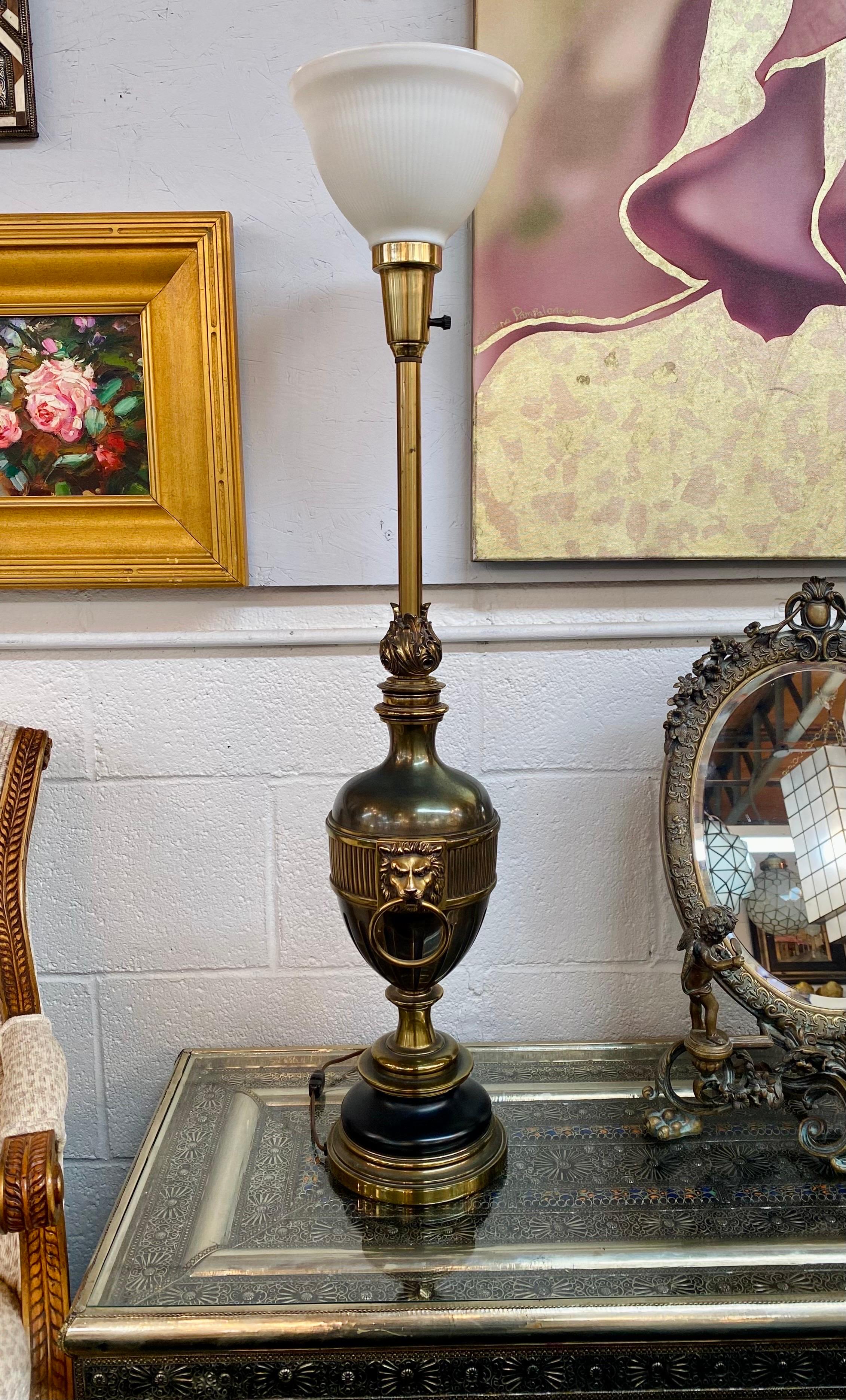 A midcentury Hollywood Regency style tall table lamp made by Stiffel Co. This classic lamp features a globe white milk shade. The two toned column is made of brass and ebony metal and shows finely carved in curvy round shape embellished with two