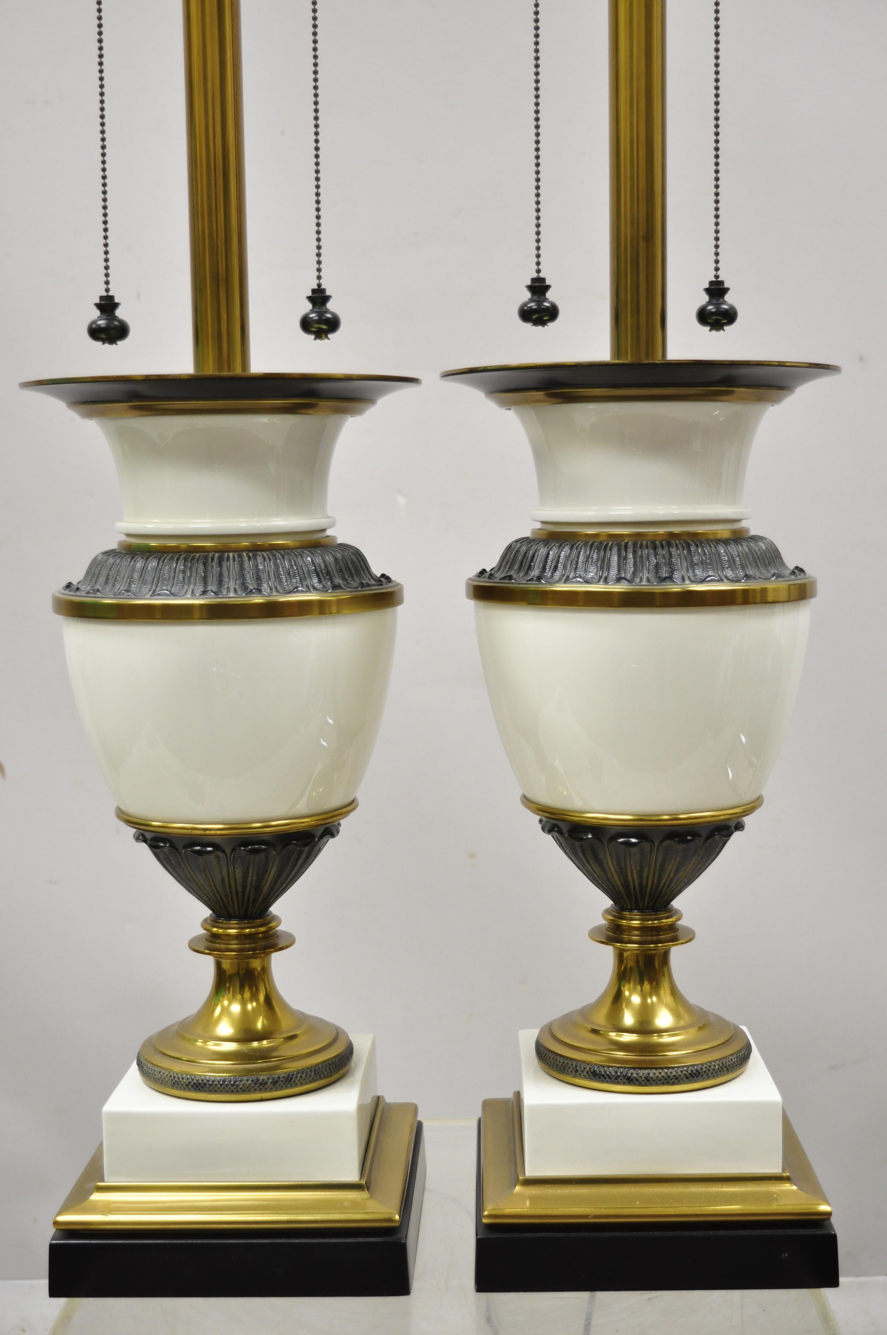 Vintage Stiffel Italian Hollywood Regency large porcelain urn brass finish tall table lamps - a pair. Item features white porcelain urn form bodies, brass plated accents, double light sockets, tall brass shaft, double ball form pulls, original