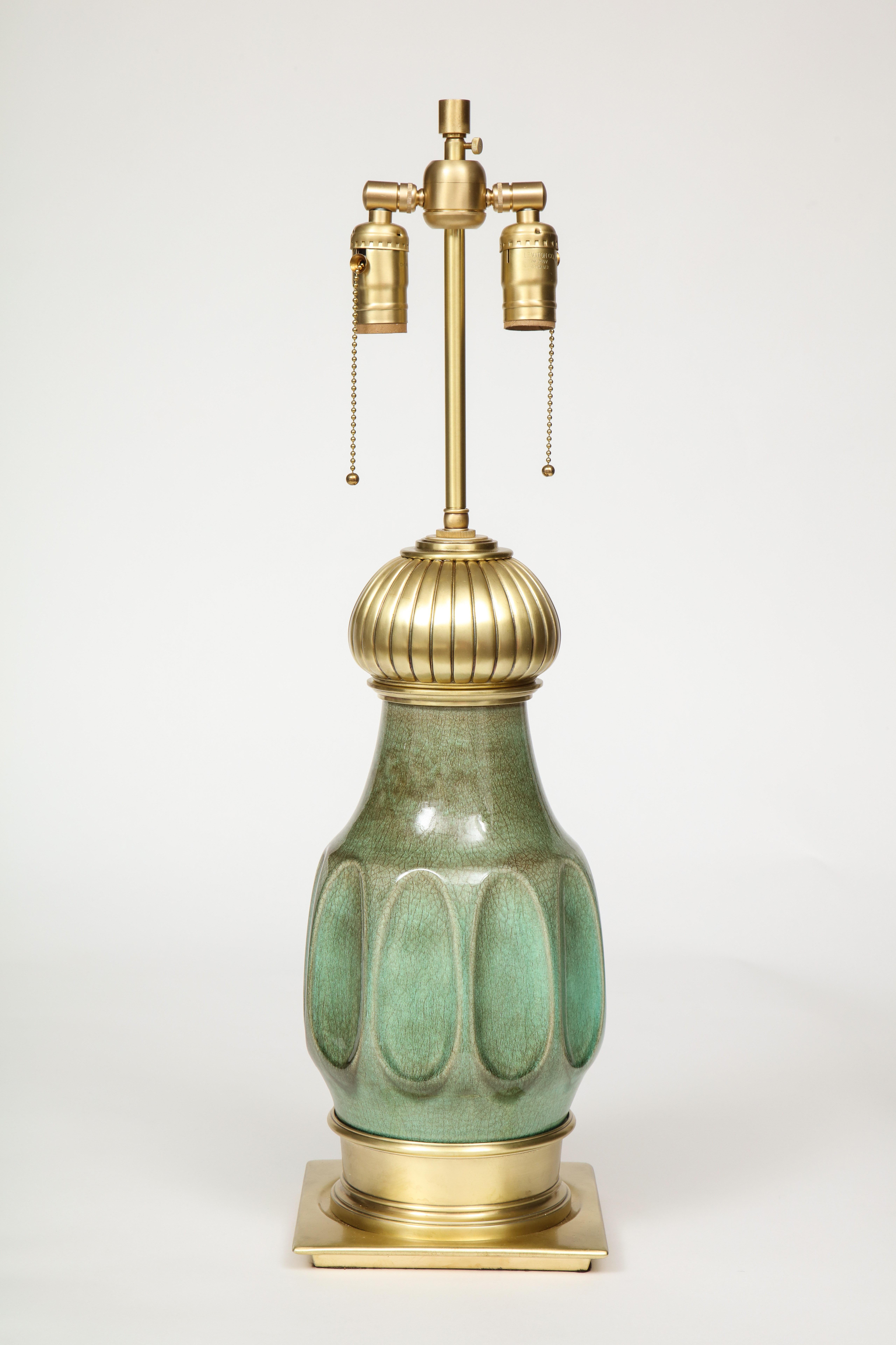Pair of Midcentury jade green glazed porcelain lamps with satin brass hardware. Lamps have been rewired for use in the USA, double cluster sockets can be height adjusted, each socket can accommodate up to 75W bulbs.