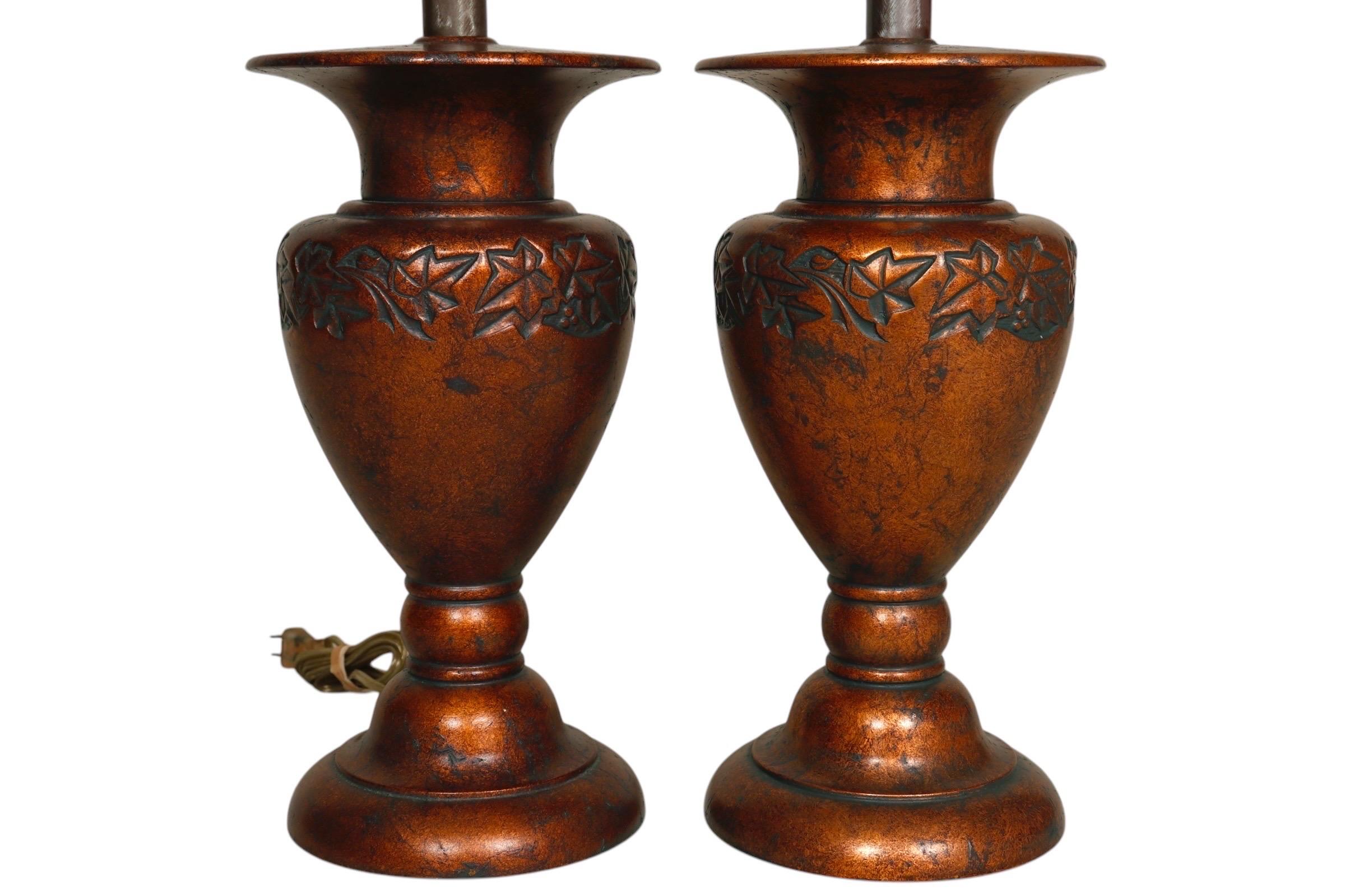 Una coppia di lampade da tavolo in stile neoclassico realizzate da Stiffel. I terminali a forma di guglia sormontano le arpe, sopra vasi a forma di urna decorati con un motivo di foglie di vite. I terminali e il corpo sono rifiniti in una ricca