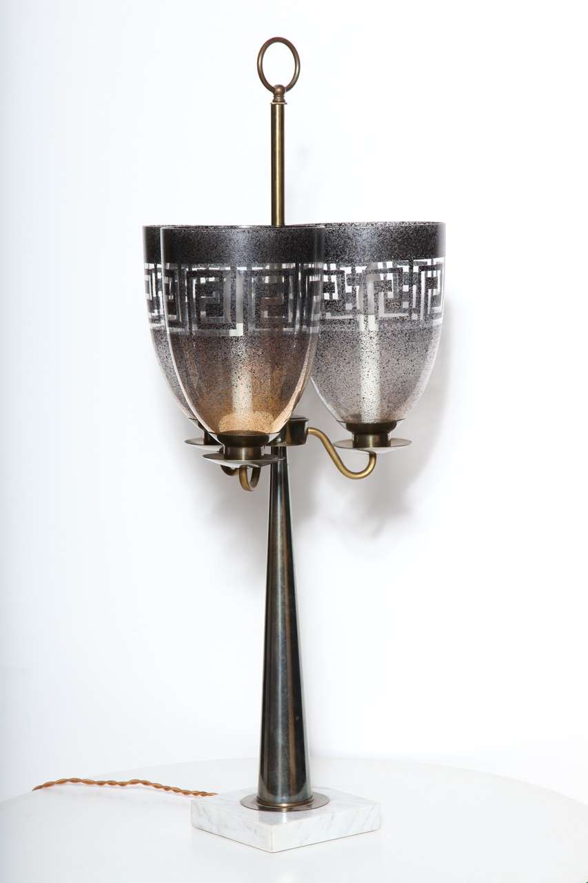 Substantial Stiffel brass and marble candlestick style table lamp with 3 frosted glass shades in the manner of Tommi Parzinger. Featuring a tall, slim brass cone column, three translucent bells shaped, 3 hurricane shades in gold to gray with Greek