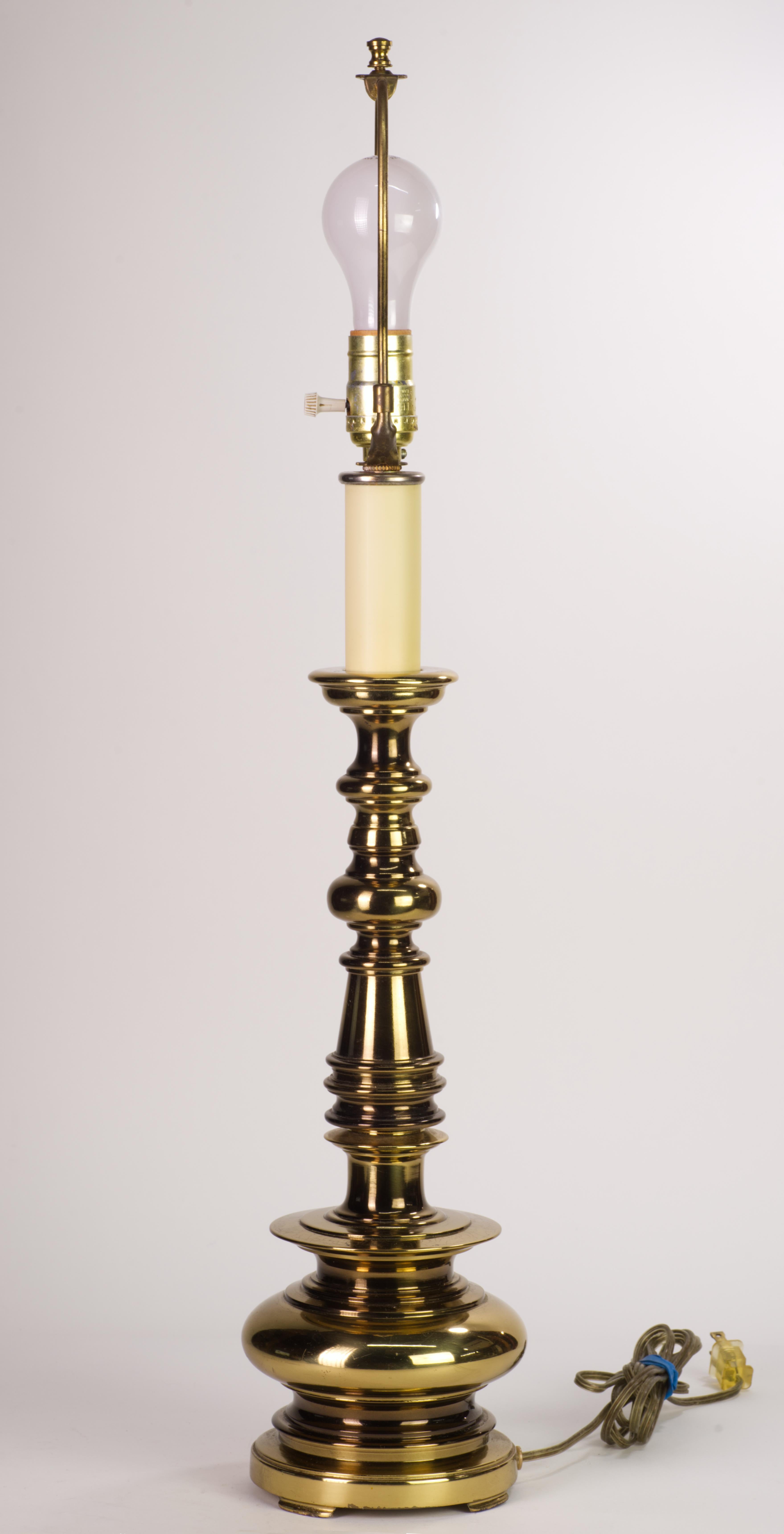  Vintage Stiffel table lamp was made with sculptural, highly detailed brass body and an off-white neck detail, creating an illusion of an ornate candlestick. The lamp has the original harp and finial.

The lamp measures 28.5