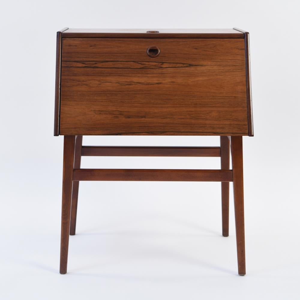 This midcentury Swedish rosewood cutlery cabinet has a fold down front with pullout / pull-out drawers, made by Stig Bolaget Malmo. With a sleek modern appearance, this is the perfect storage place for cutlery and comes with a set of flatware and