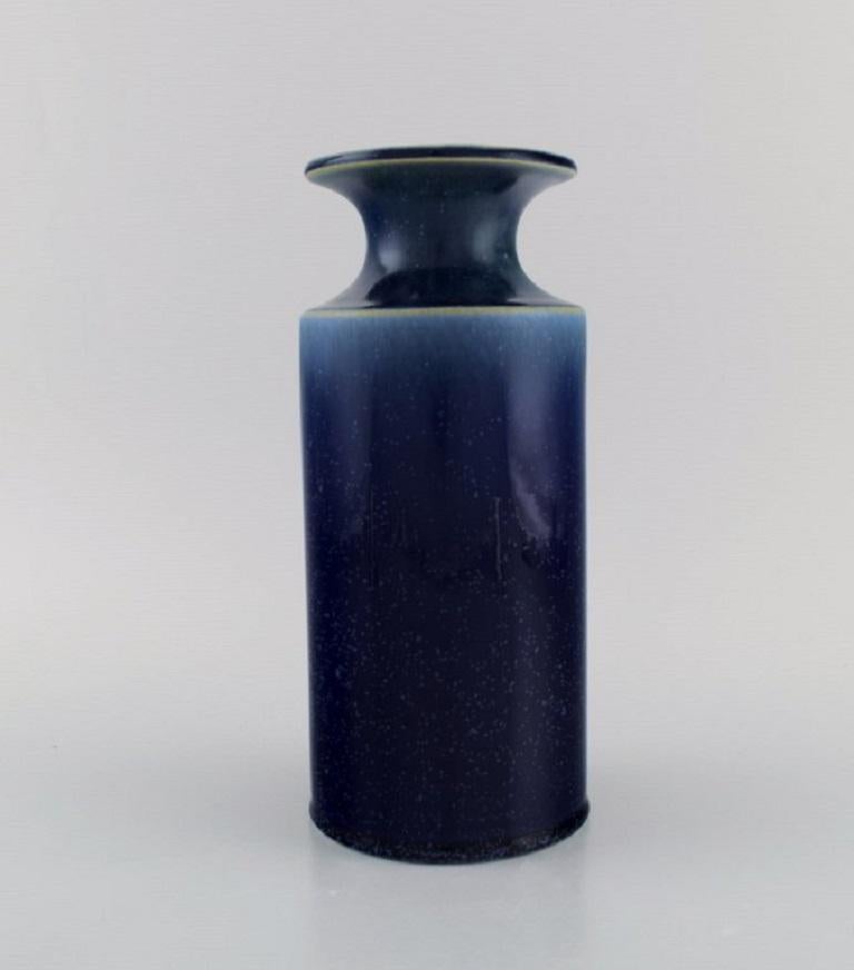 Stig Lindberg (1916-1982) pour Gustavsberg. 
Vase en céramique émaillée. Magnifique glaçure mouchetée dans des tons de bleu. 
Design suédois, milieu du 20e siècle.
Mesures : 24.5 x 10,5 cm.
En parfait état.
Autocollant.