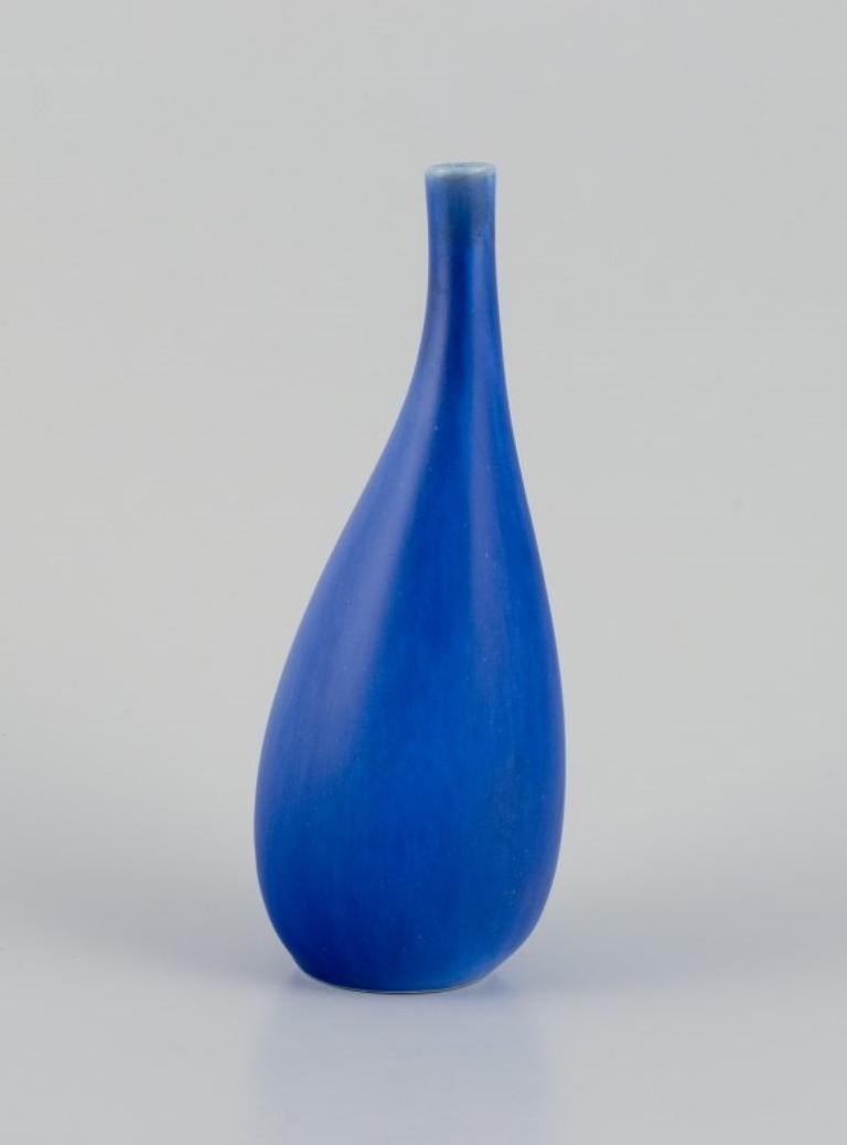 Stig Lindberg for Gustavsberg, Sweden. 
Ceramic vase with a slender neck. Glazed in blue tones.
Approximately from the 1960s.
In perfect condition.
Dimensions: Height 22.5 cm x Diameter 8.5 cm.
