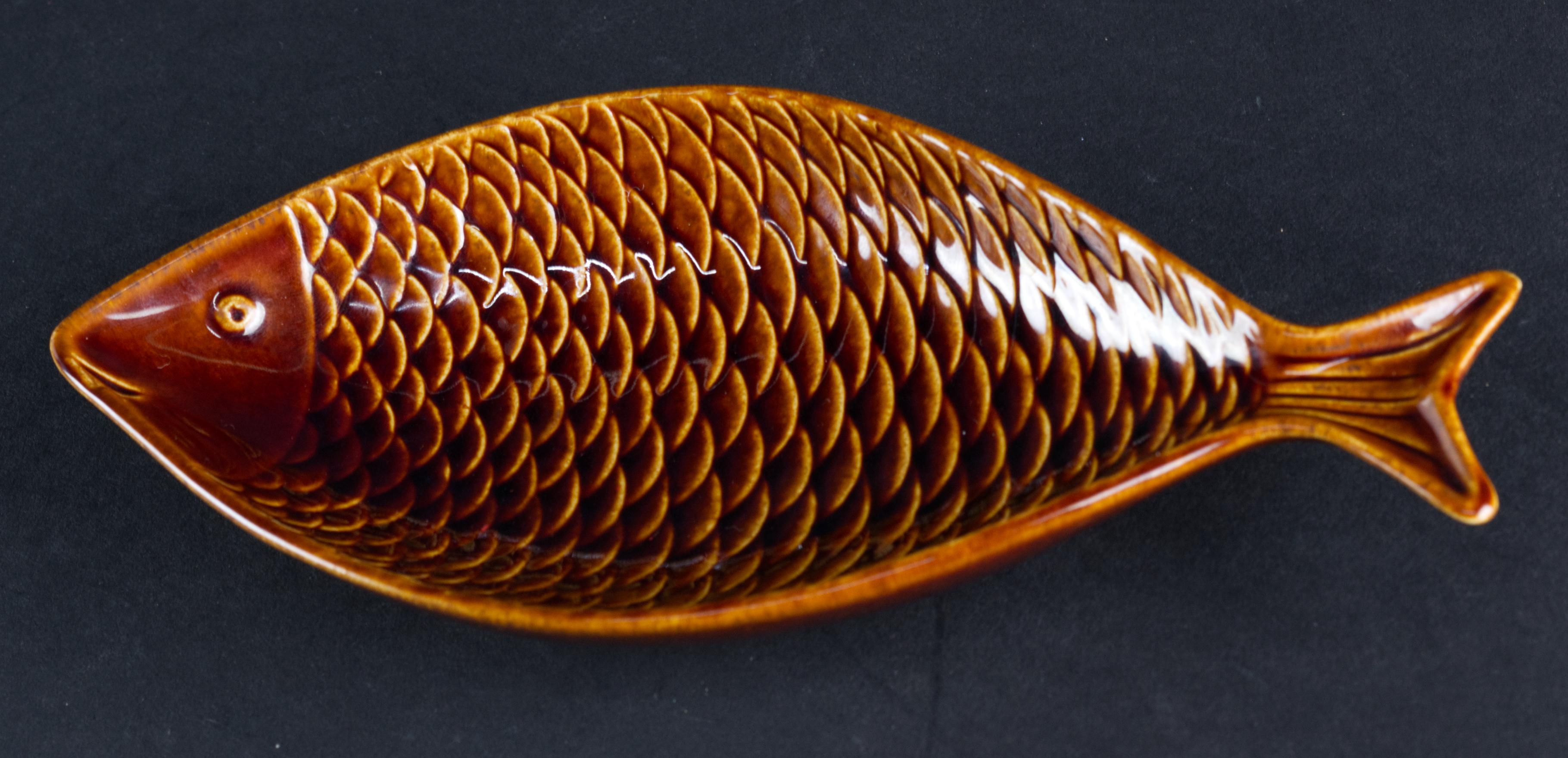  Fladen series was designed by Stig Lindberg for Gustavsberg Sweden in 1958.  The dish is formed in shape of a fish with beautifully detailed scales done in relief. Glossy warm brown glaze continues on outer surfaces of the dish; the bottom is