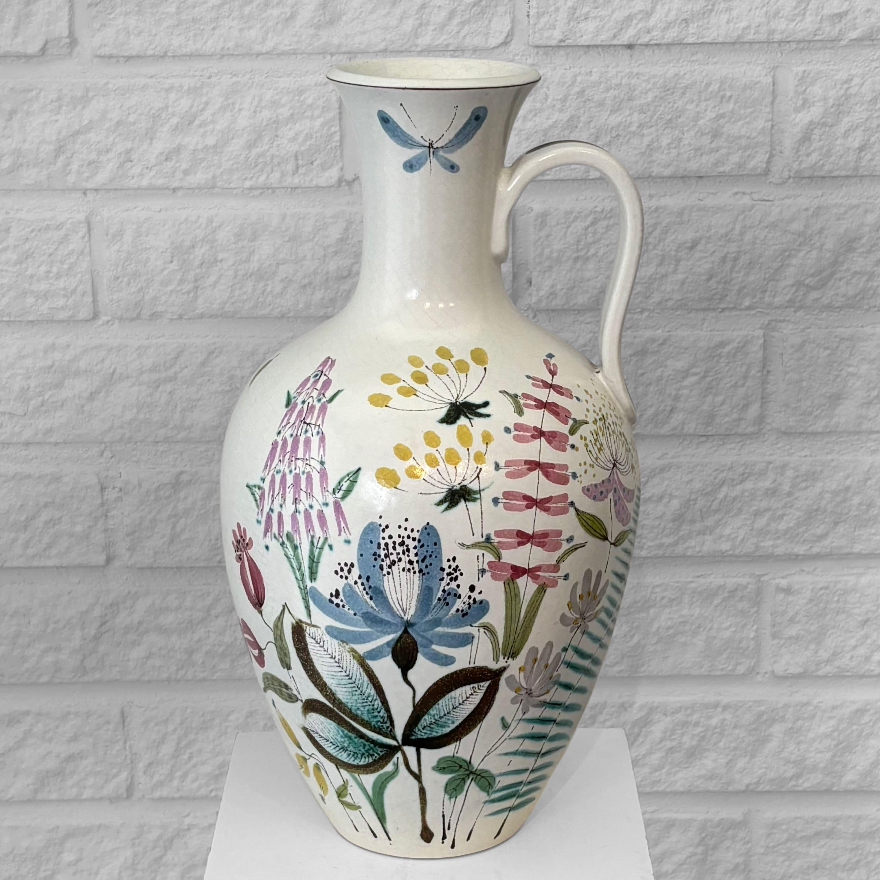 A large faience vase, model 116 F.10, designed by Swedish ceramicist Stig Lindberg for Gustavsberg Studio in the 1940s. A hand-turned urn-shaped vessel with an applied handle, glazed in eggshell white and decorated with a polychrome floral pattern