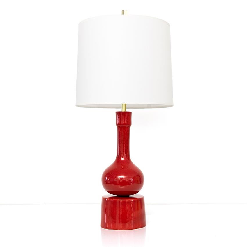 A shiny red glazed ceramic lamp by Swedish artist and ceramicist Stig Lindberg for Gustavsberg. The lamp consist of two ceramic parts, a polished brass stem which holds a new double cluster of standard base sockets. Wired for use in the USA.