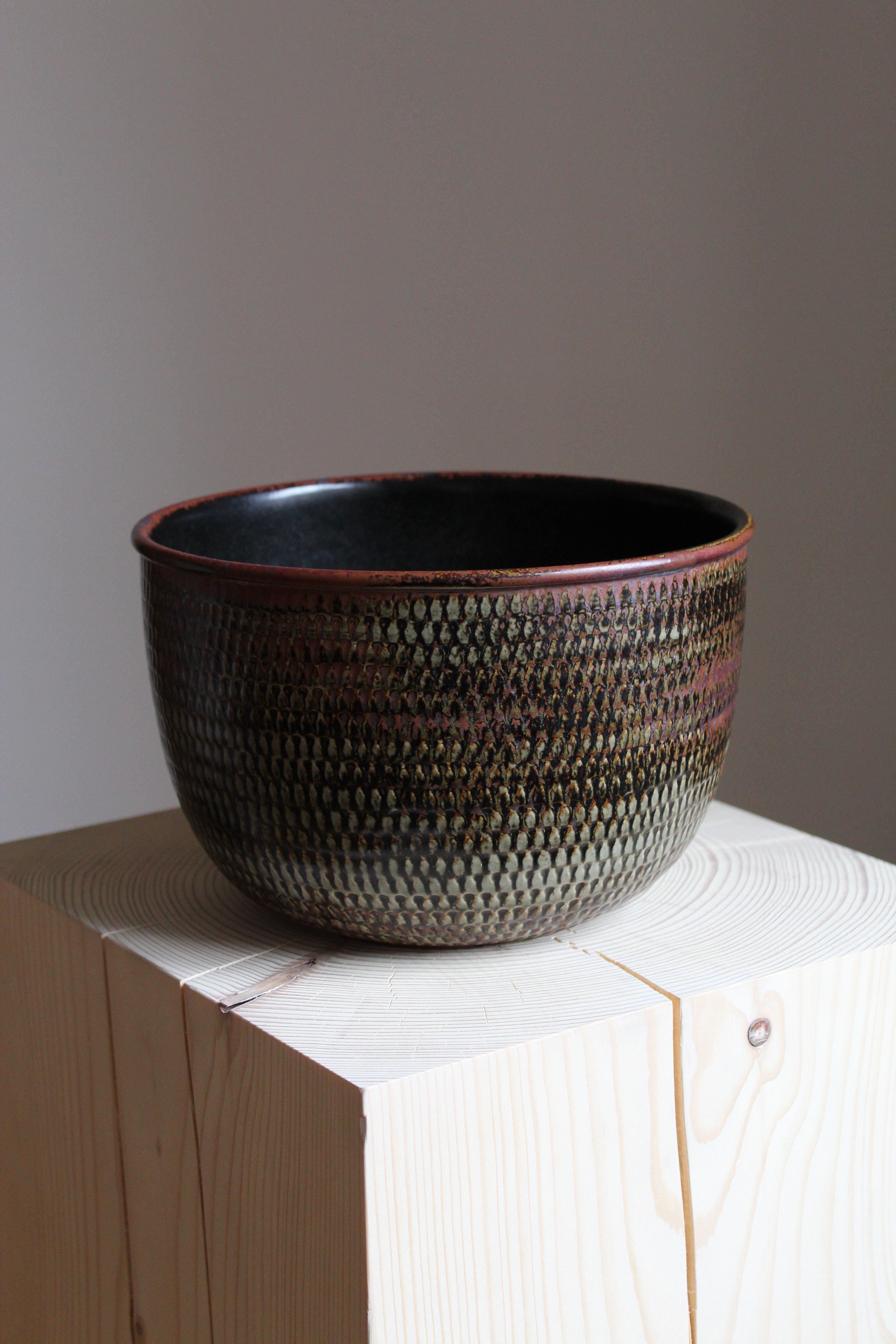An unique sizable decorative bowl. Designed by Stig Lindberg, produced by Gustavsberg, 1960s. Features a highly complex and artistic glaze in Lindbergs signature style, signed and marked with the stylized hand, indicating it's a studio