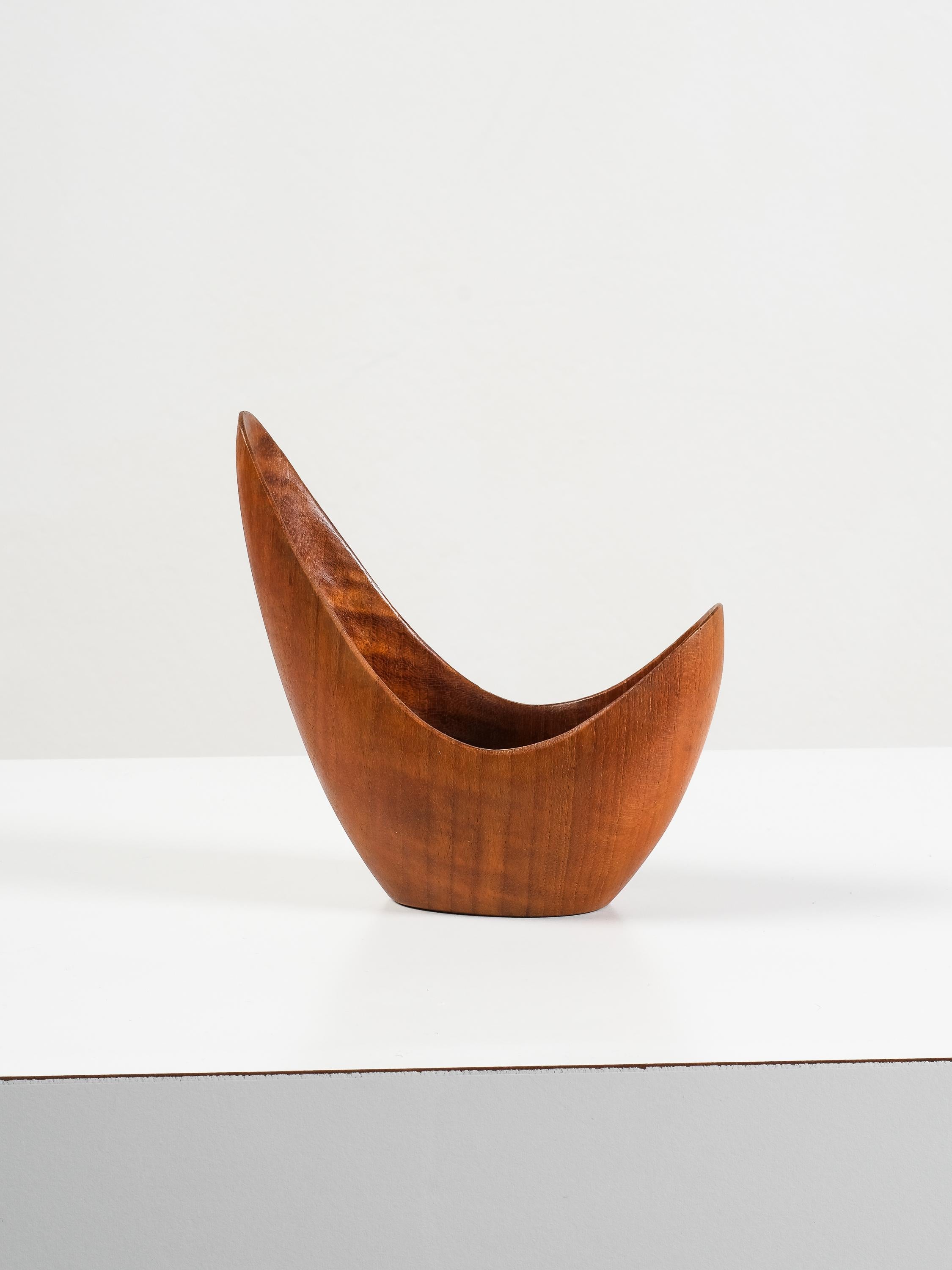 Cet élégant petit bol de Stig Sandqvist illustre le modernisme organique du design scandinave des années 1950. Sculptée à la main dans un teck riche et doré, la pièce est définie par sa forme fluide et sculpturale - un jeu de lignes courbes et de