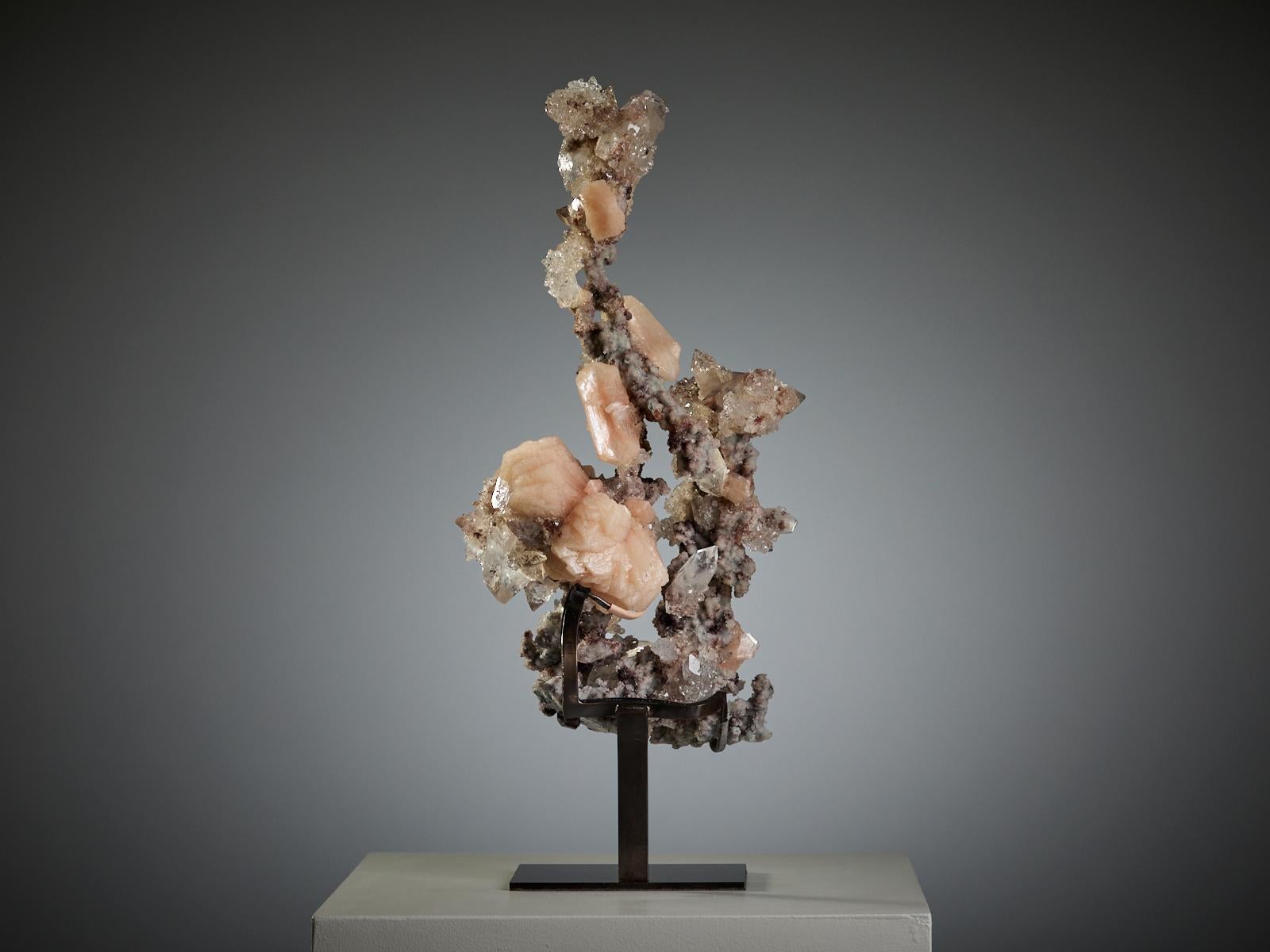 A delicate and elegant specimen from India, featuring soft pink stilbite and creamy calcite crystals of different sizes, all resting on a base of chalcedony quartz.

The arrangement forms a tall, sculptural composition — almost like a natural column