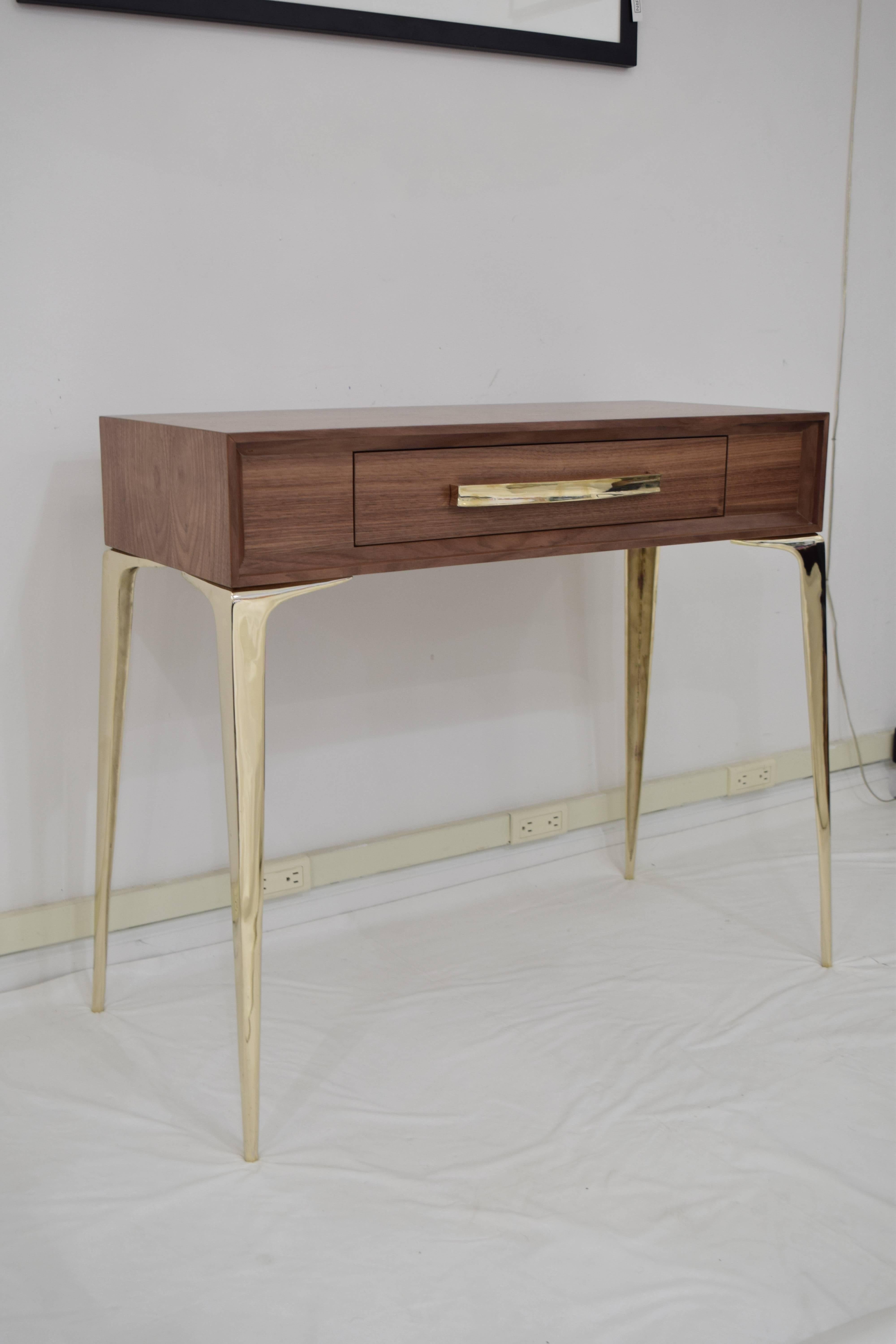 The Stiletto single drawer console, designed by Irwin Feld Design for CF Modern, boasts clean and sculptural lines. As shown, made in true natural walnut, with brass metal accents supporting a single-drawer top with hand cast brass legs and bar