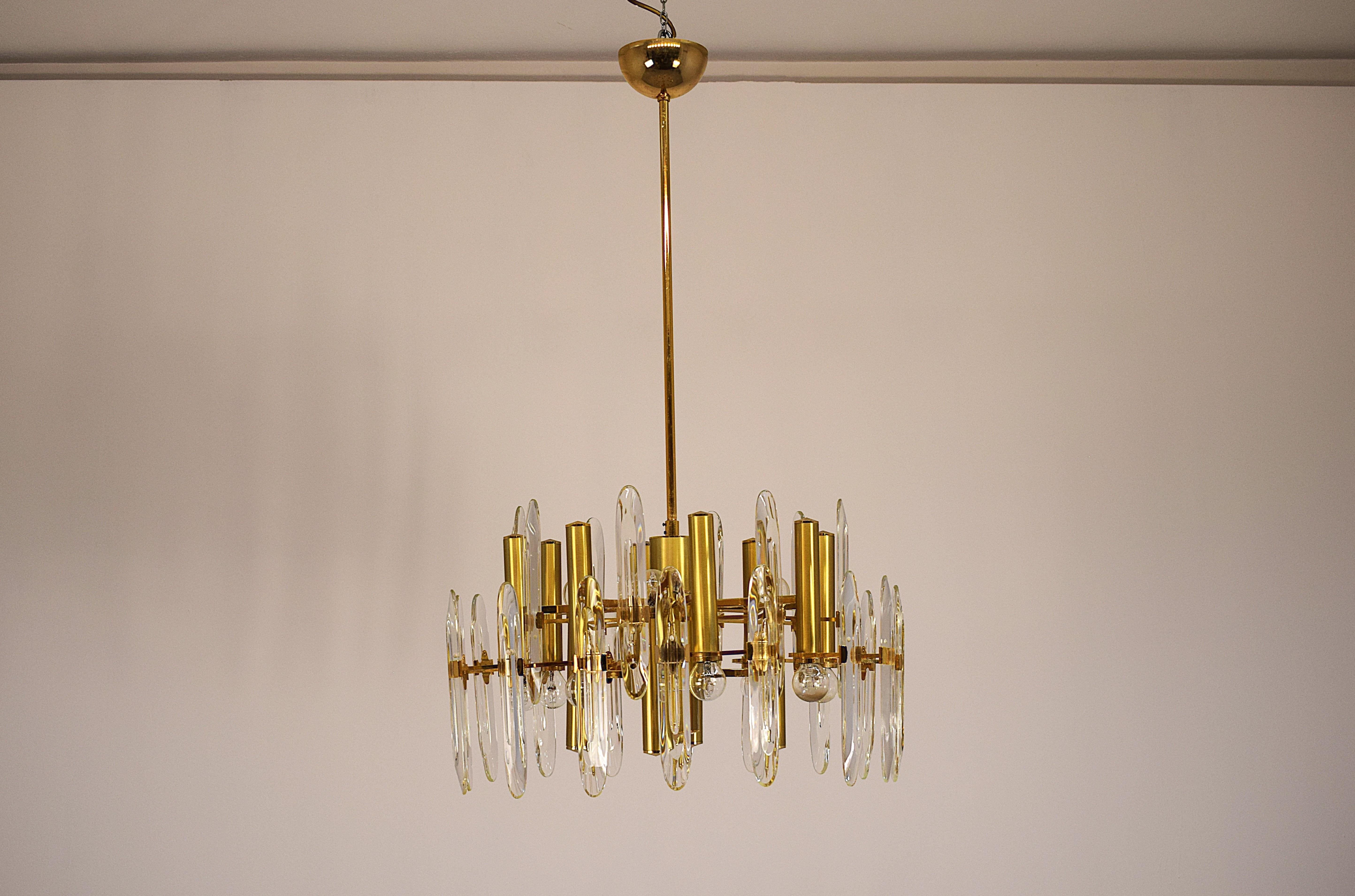 Elegante coppia di lampadari Stilkronen risalenti agli anni '70, autentico esempio di design italiano. Realizzati con struttura in metallo dorato e vetri decorativi, questi lampadari combinano stile classico e fascino vintage. Ogni lampadario misura
