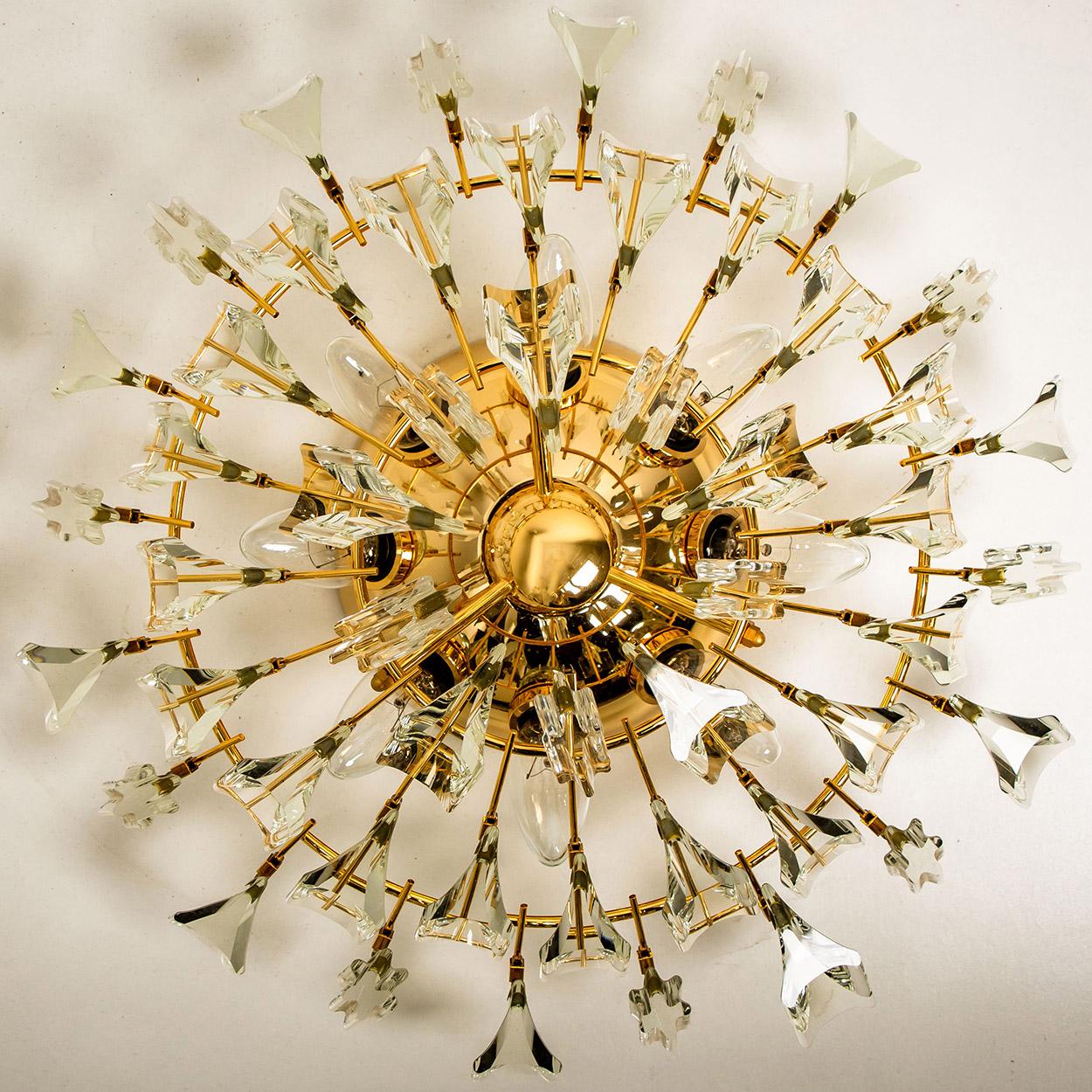 High-end gilded brass flush mount by Stilkronen, made in Italy, circa 1975, featuring a sunburst array of branches holding 30 clear crystals pieces. The crystals refract light beautifully and are perfect for a soft, warm and welcoming glow in the