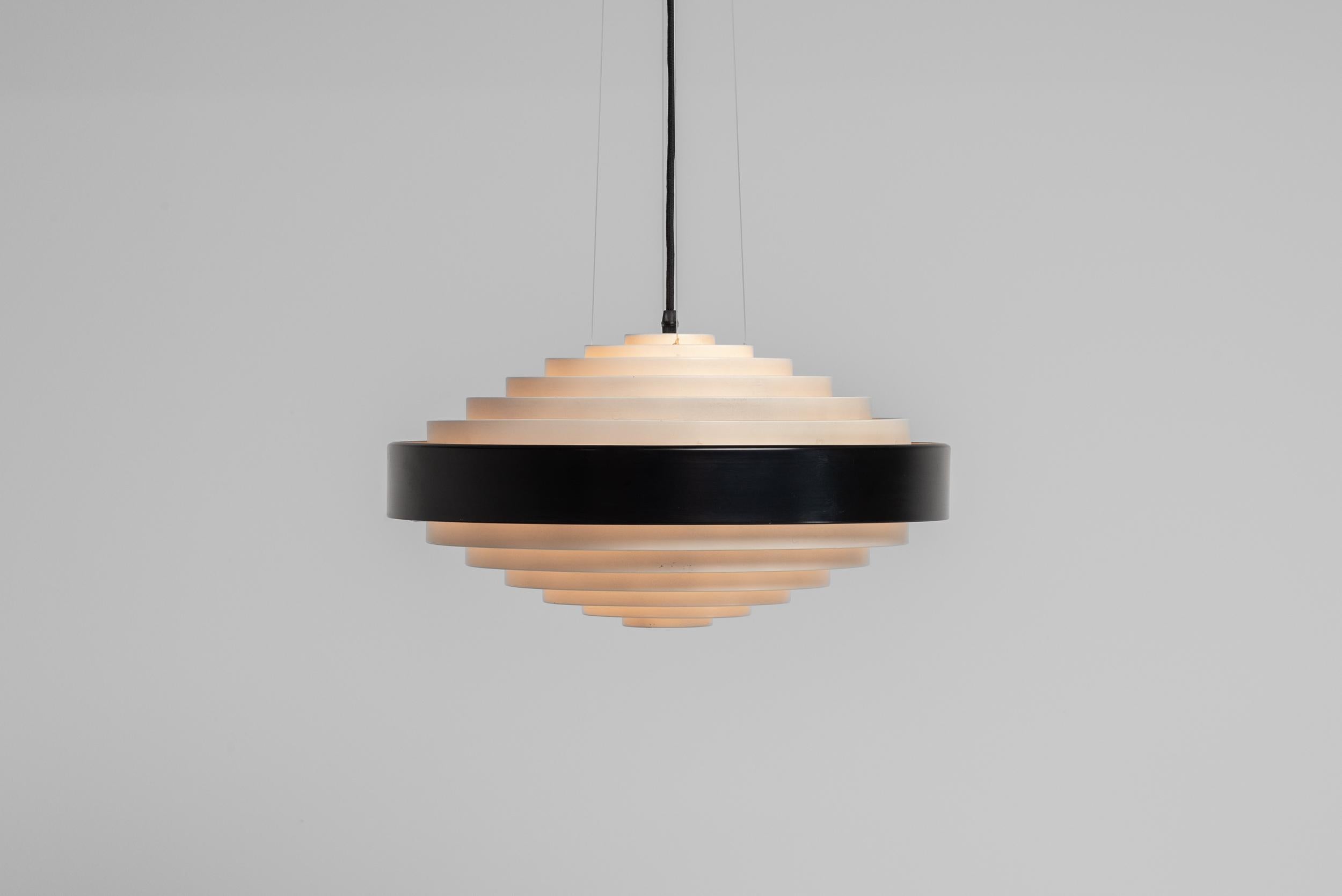 Wonderful 1088 chandelier designed by Bruno Gatta and manufactured by Stilnovo in Italy in 1959. This stunning ceiling pendant lamp is a nice example of innovative mid-century modern design. The lamp features a striking shade made of lacquered rings