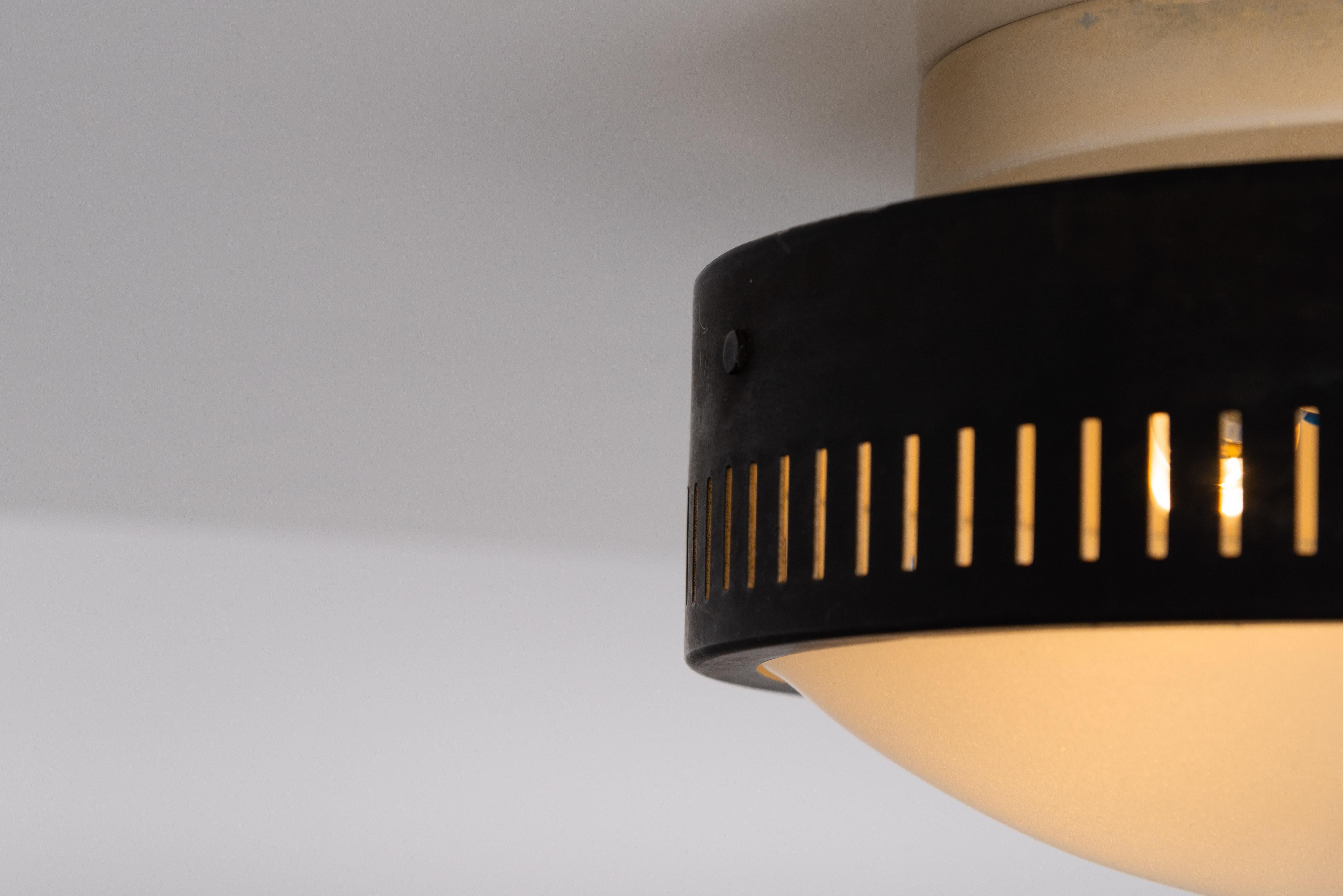 Minimalistic black ceiling lamps designed by Stilnovo and manufactured in Italy in 1960. An interesting feature are the die-cut diffuser patterns along the rim, which creates a beautiful light effect. Each lamp has the Stilnovo sticker on the
