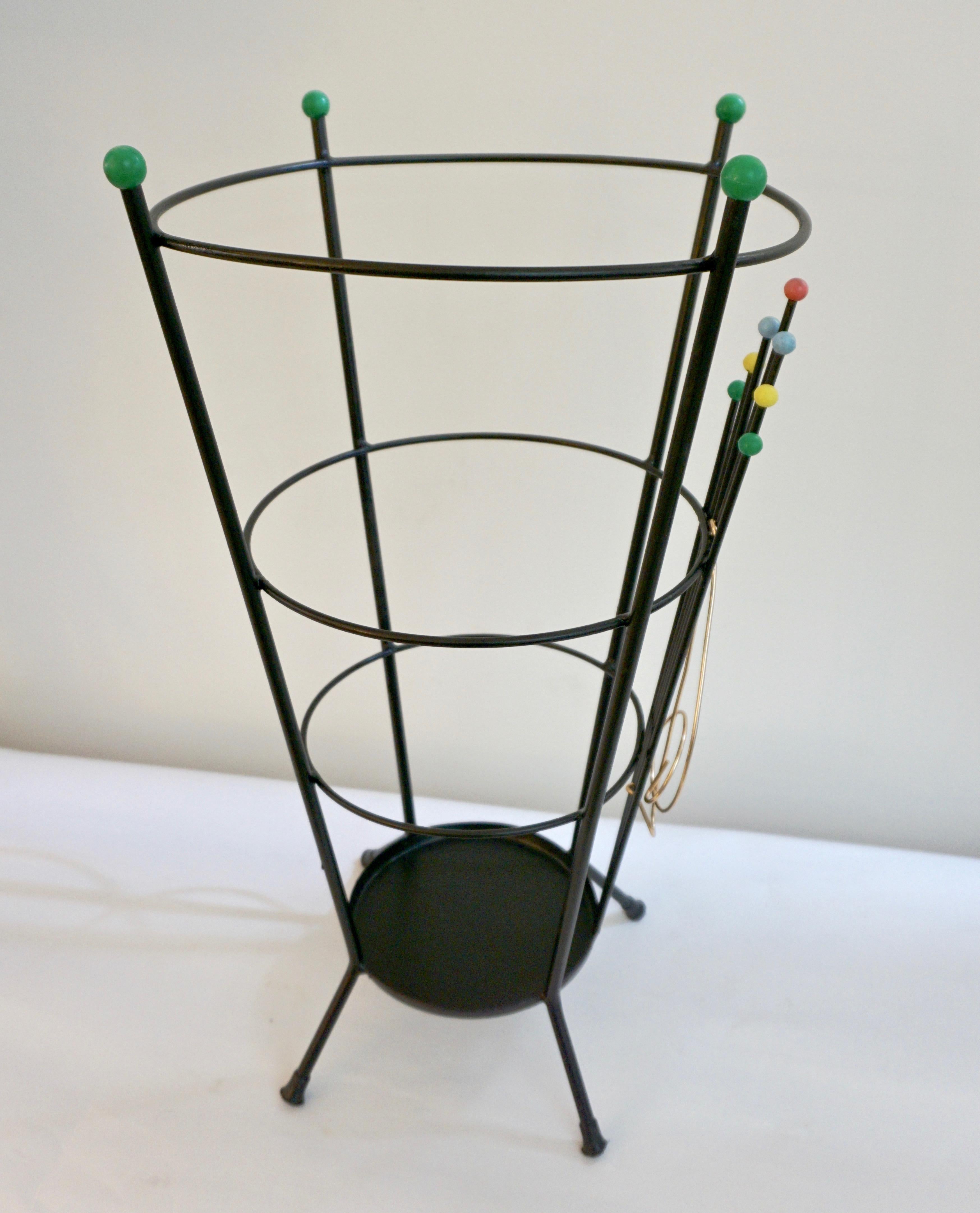 A delightful Italian umbrella stand by Stilnovo in black lacquered metal of conical flared shape, the minimalist modern design of the metal rods encircling the upright supports is gently highlighted on the front by a music clef in brass and