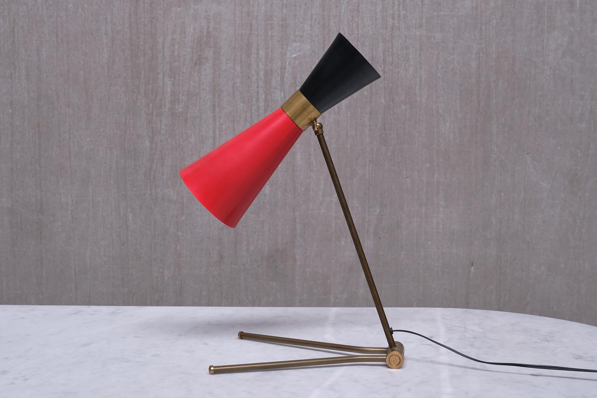 This very rare desk/table lamp was produced by Stilnovo in Italy in the mid 1950s.

The striking design is defined by the elongated diabolo shaped shade. The steel shades that have been coated with lacquer in striking red and black hues, separated