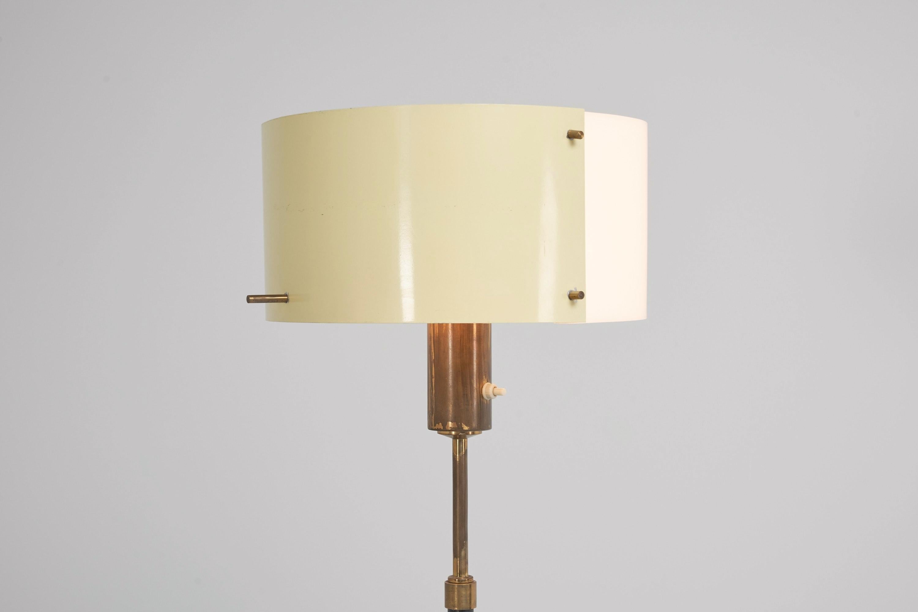 Minimalistic adjustable floor lamp designed and manufactured by Stilnovo, Italy, 1950. This floor lamp has a tripod base in black painted metal, it features brass tipped feet which look like the spacecraft landing gear where many lamp designs from
