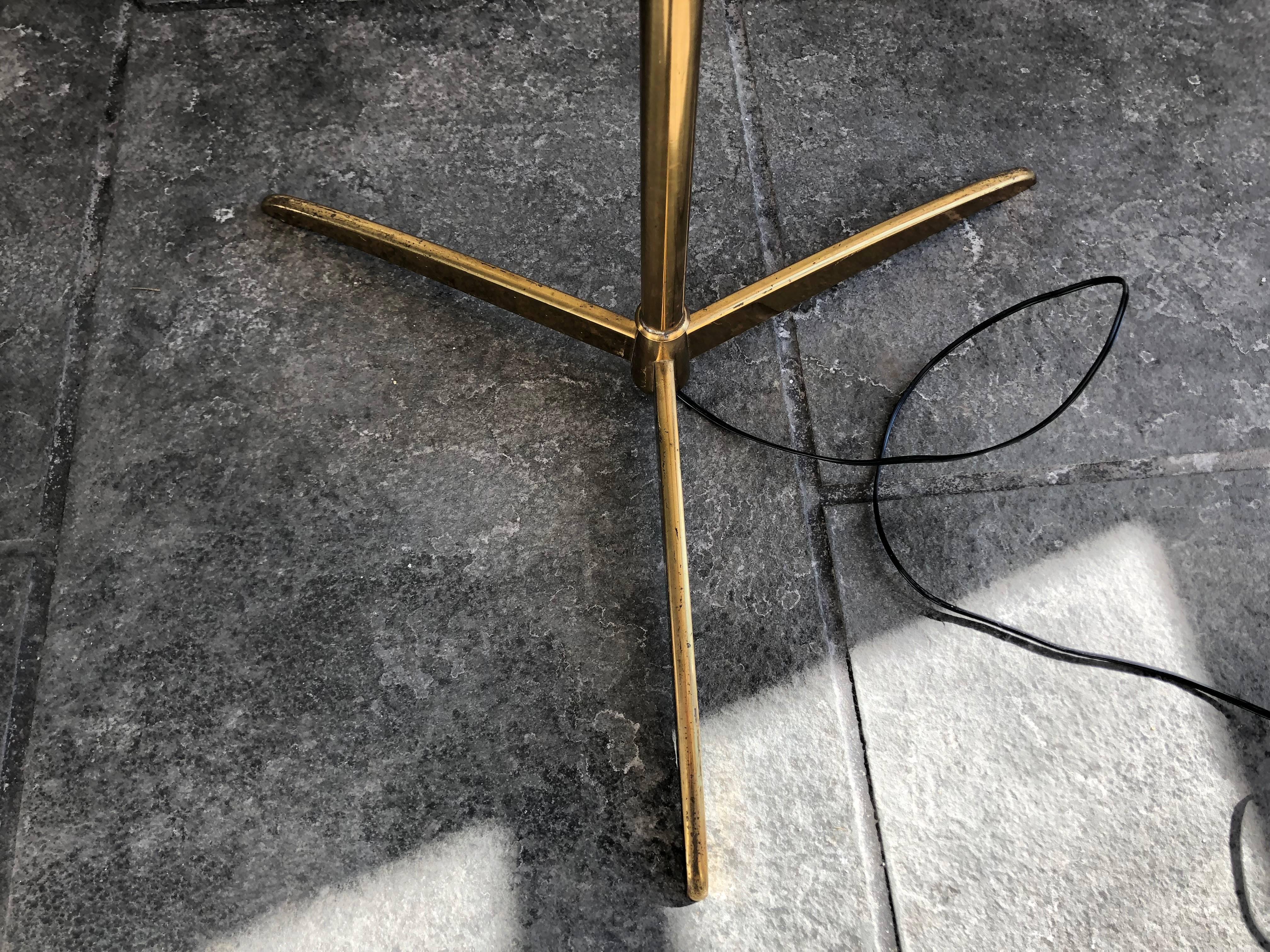 Stilnovo brass floor lamp torchere from the 1950s, all original parts, with enameled over-scaled up shade, mounted on three brass feet. This lamp has a single pole with leather turn adjustment in center allowing a height of between 54