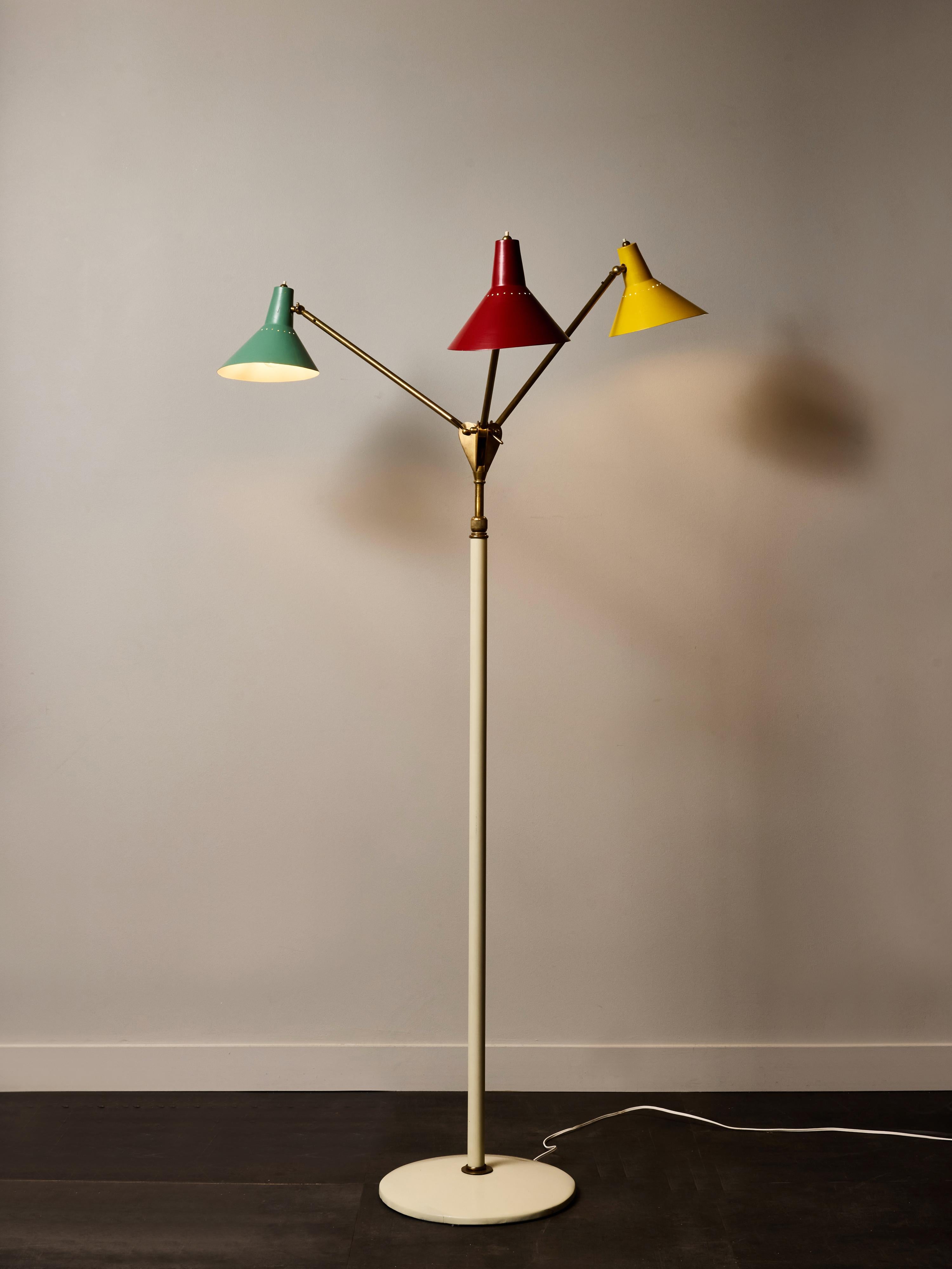 Elegante y funcional lámpara de pie de Stilnovo, con vástago central regulable en altura y tres brazos de latón regulables independientemente. Cada brazo soporta una pantalla metálica cónica de un color original diferente que añade un equilibrio
