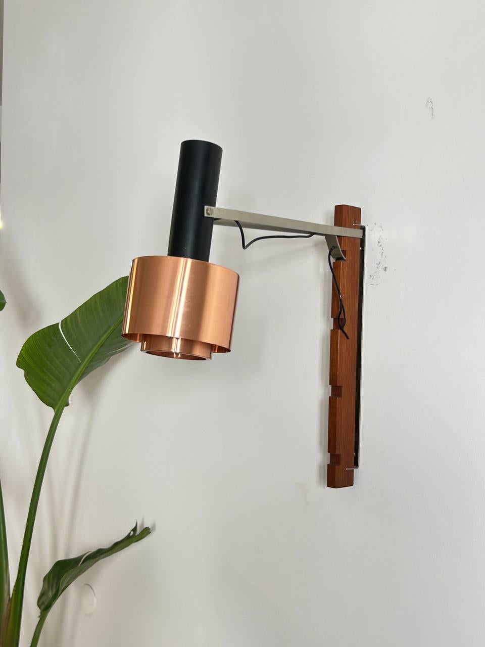 Grande lampada da muro Stilnovo regolabile in altezza su quattro livelli e orientabile in verticale. 

Legno e metallo in ottime condizioni, viti originali, paralume in rame presenta dei graffi neri non profondi che possono essere rimossi.

