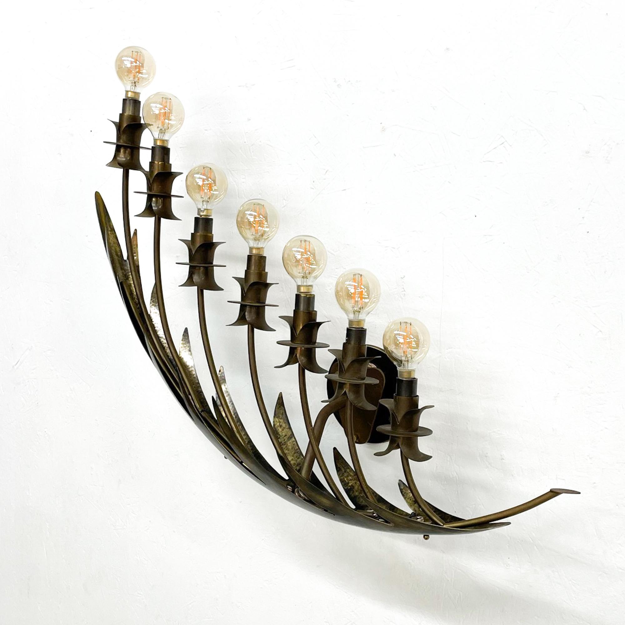 Italy 1950s wall sconce seven arm lamp in stamped brass.
modern wall sconce by Stilnovo 
attributed to Gino Sarfatti 
Made in Italy.
Maker stamped on petal Stilnovo
 11 H x 29 W x 6.5 D inches
Original unrestored vintage condition. Patina present.