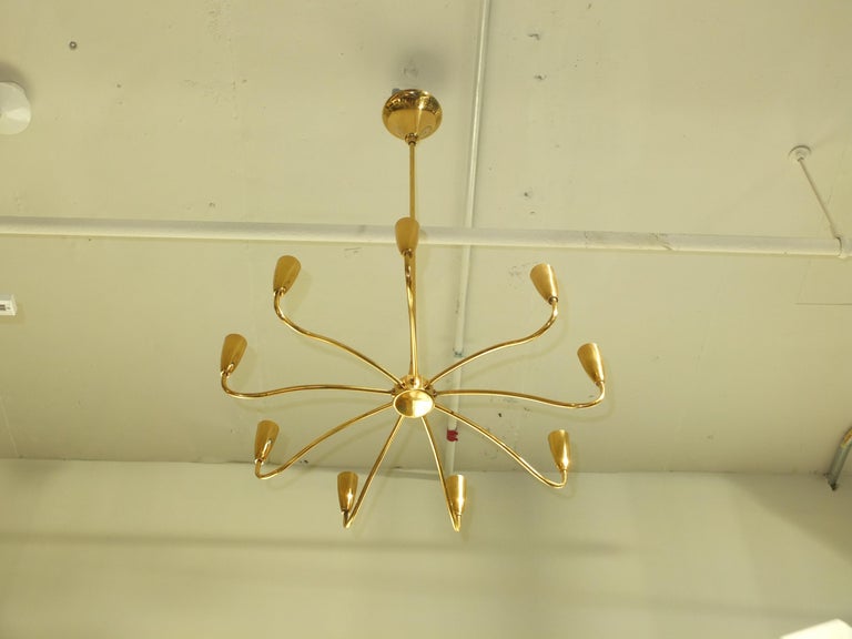 Simple and elegant solid brass chandelier made in Italy by Stilnovo in the late 1950's early 1960's with nine sinuously curved arms off a central hub terminating with gracefully flared goblet cones as light cups. Each socket takes a 60 volt