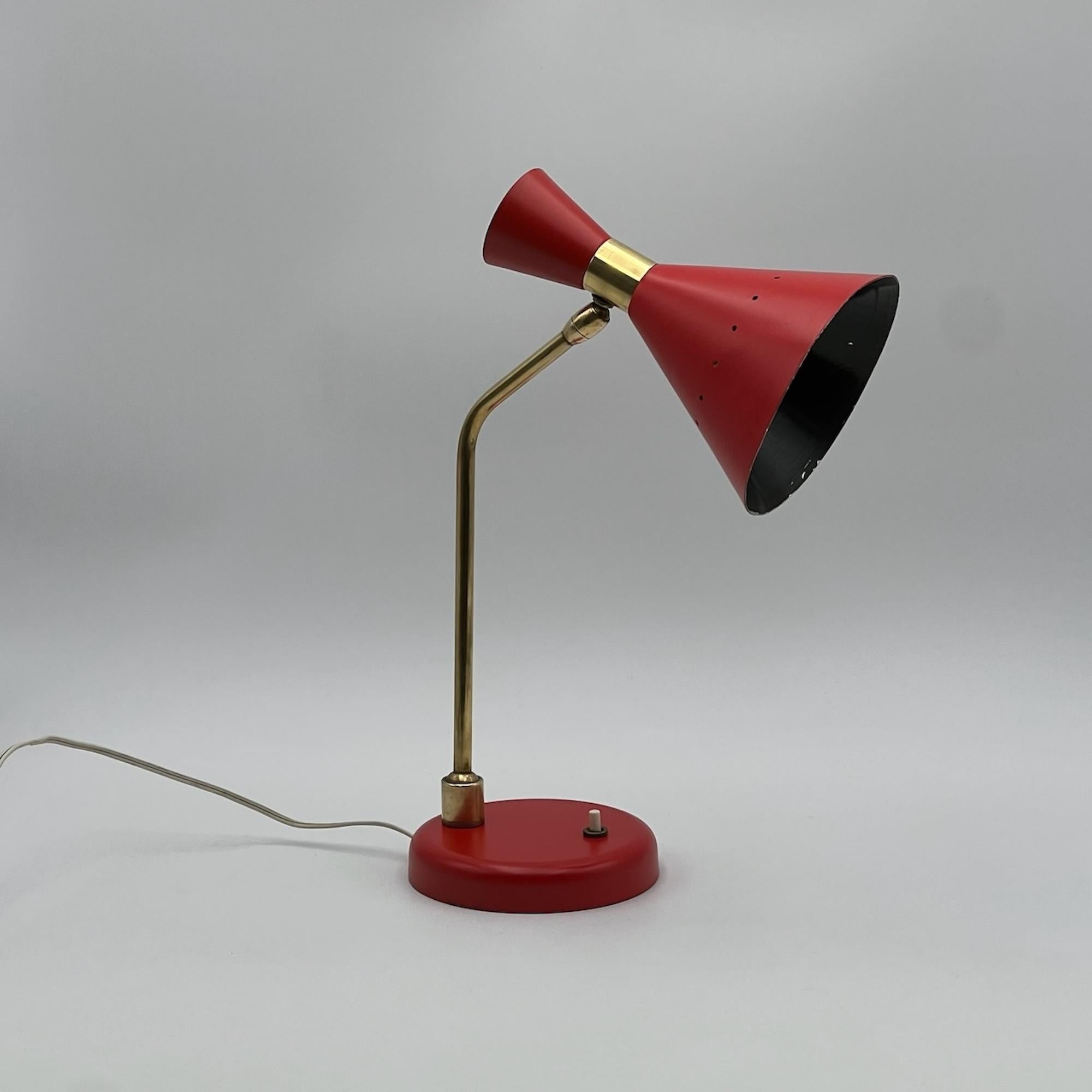 Lovely vintage lamp with a distinctive double cone shape, an adjustable brass stem and lacquered red metal lampshade and base, attributable to the iconic maker Stilnovo, Italy.

The lampshade has an peculiar shape that resembles a megaphone. The