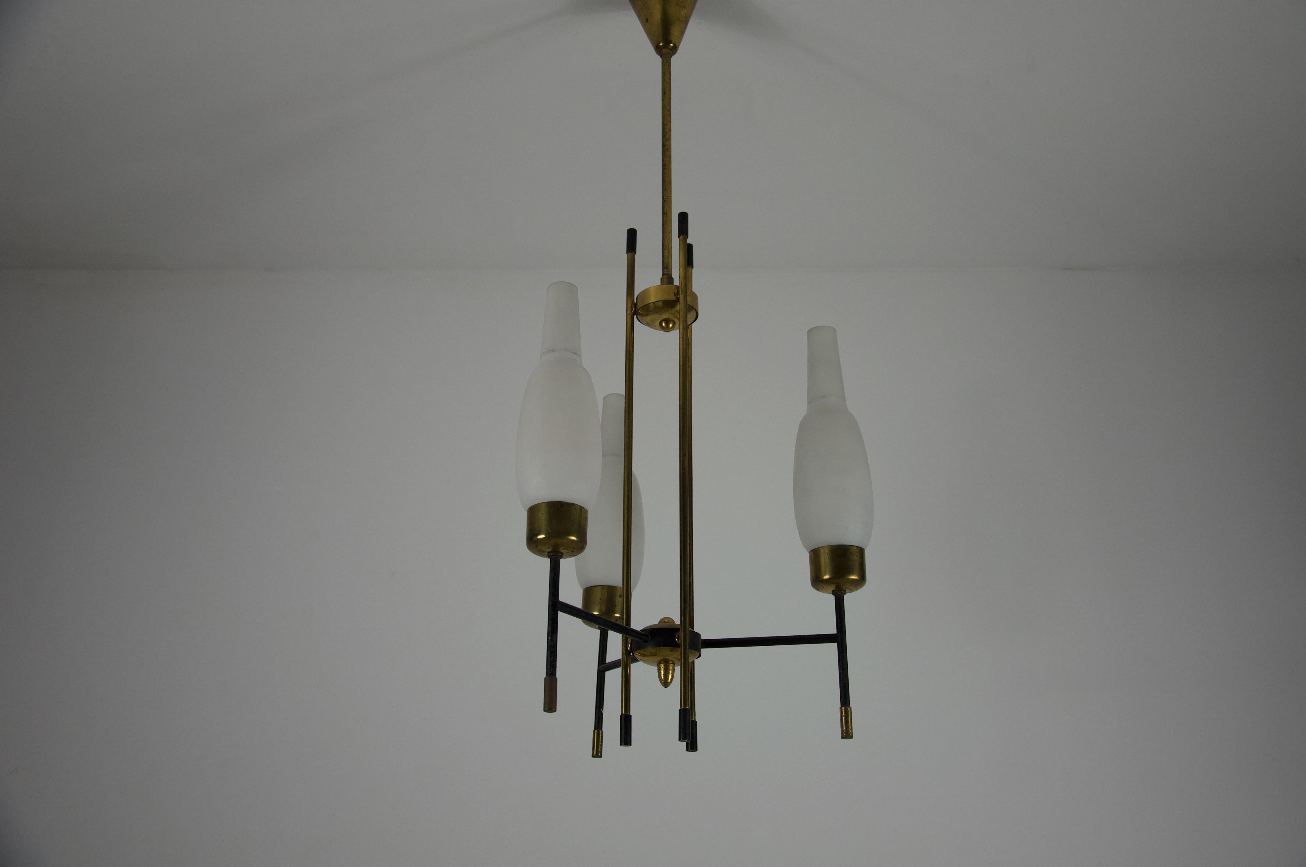 Ce magnifique lustre italien est un exemple classique du design moderne du milieu du siècle, attribué au style renommé de Stilnovo et datant des années 1960. Le luminaire présente une structure convaincante fabriquée à partir de laiton poli et