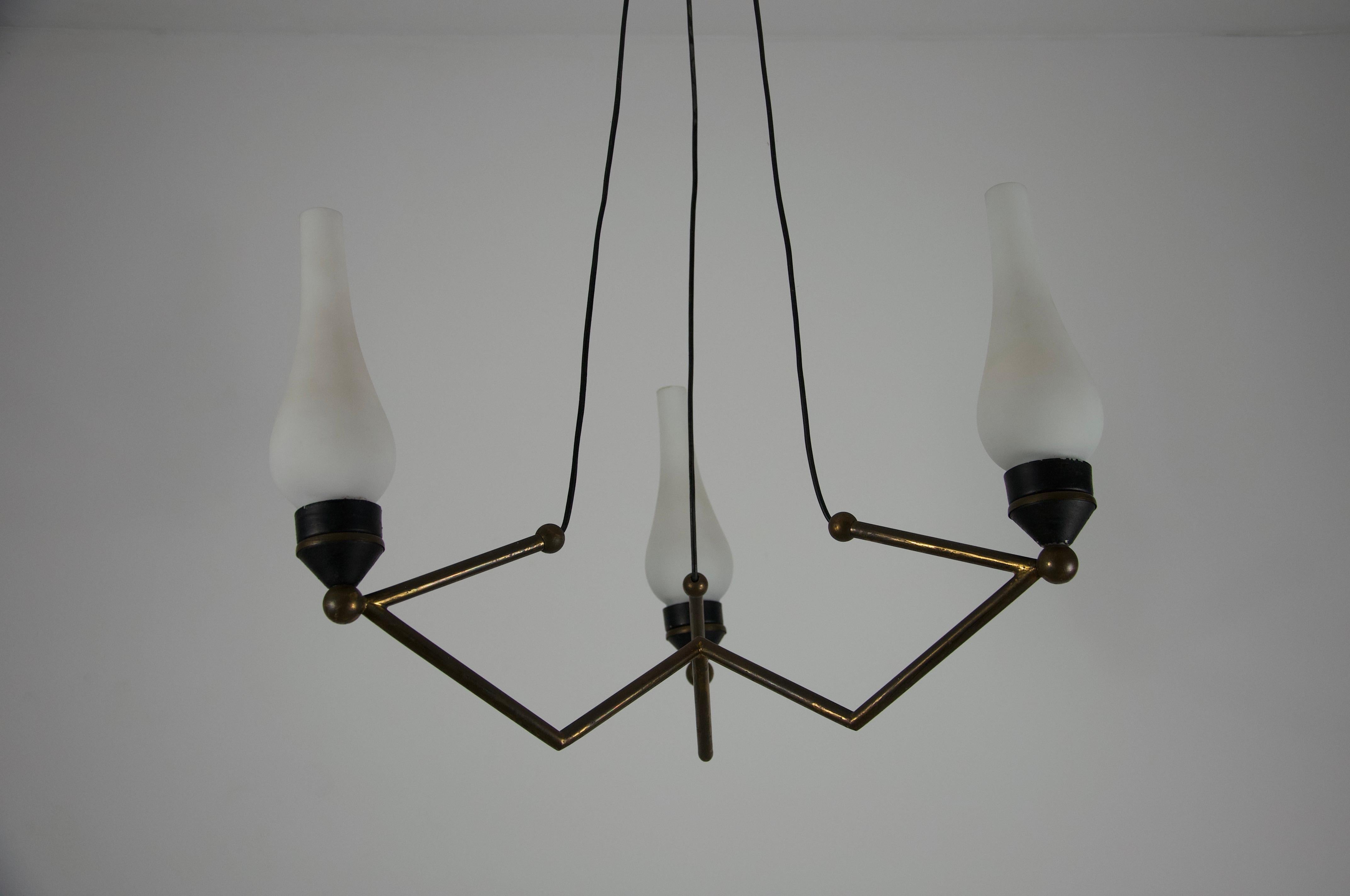 Cet élégant lustre, fabriqué par Stilnovo en Italie dans les années 1960, illustre l'esthétique moderniste et raffinée qui a fait la renommée de la marque. Le luminaire présente un cadre géométrique en laiton avec des lignes nettes et angulaires qui