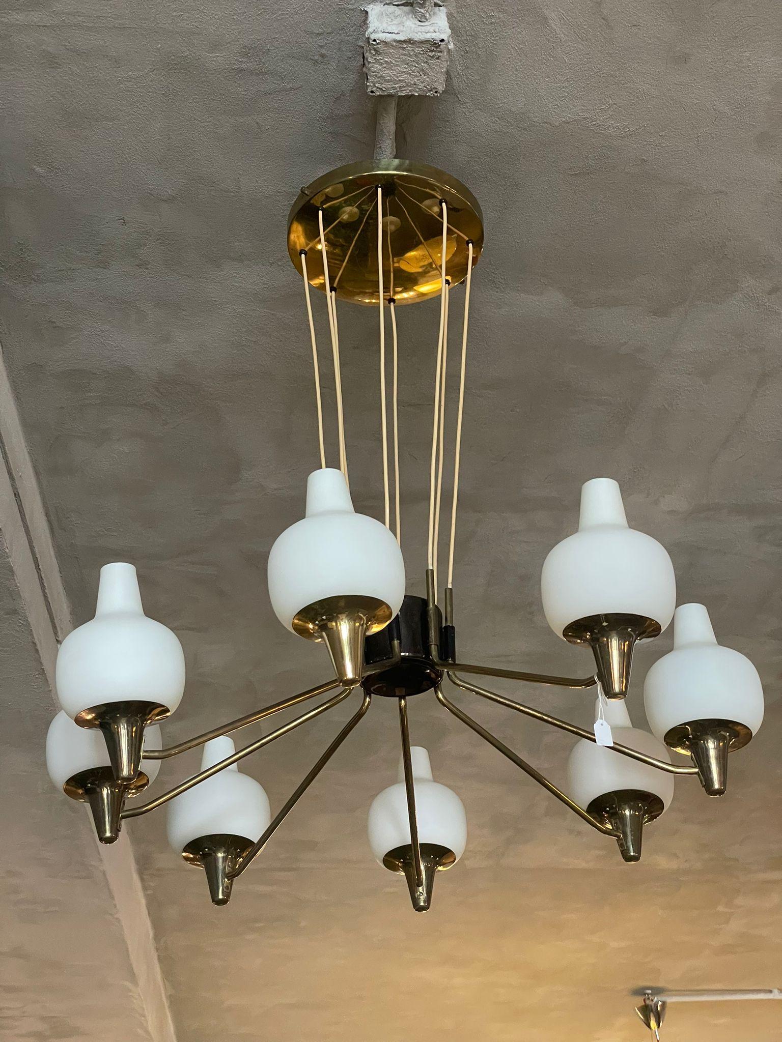 Brass chandelier manufactured by Stilnovo, in Italy, 1950s.
The chandelier on the ceiling has a circular brass plate from which are present eight cables that converge in the black structure from which the eight arms branch off.
Each of eight arms